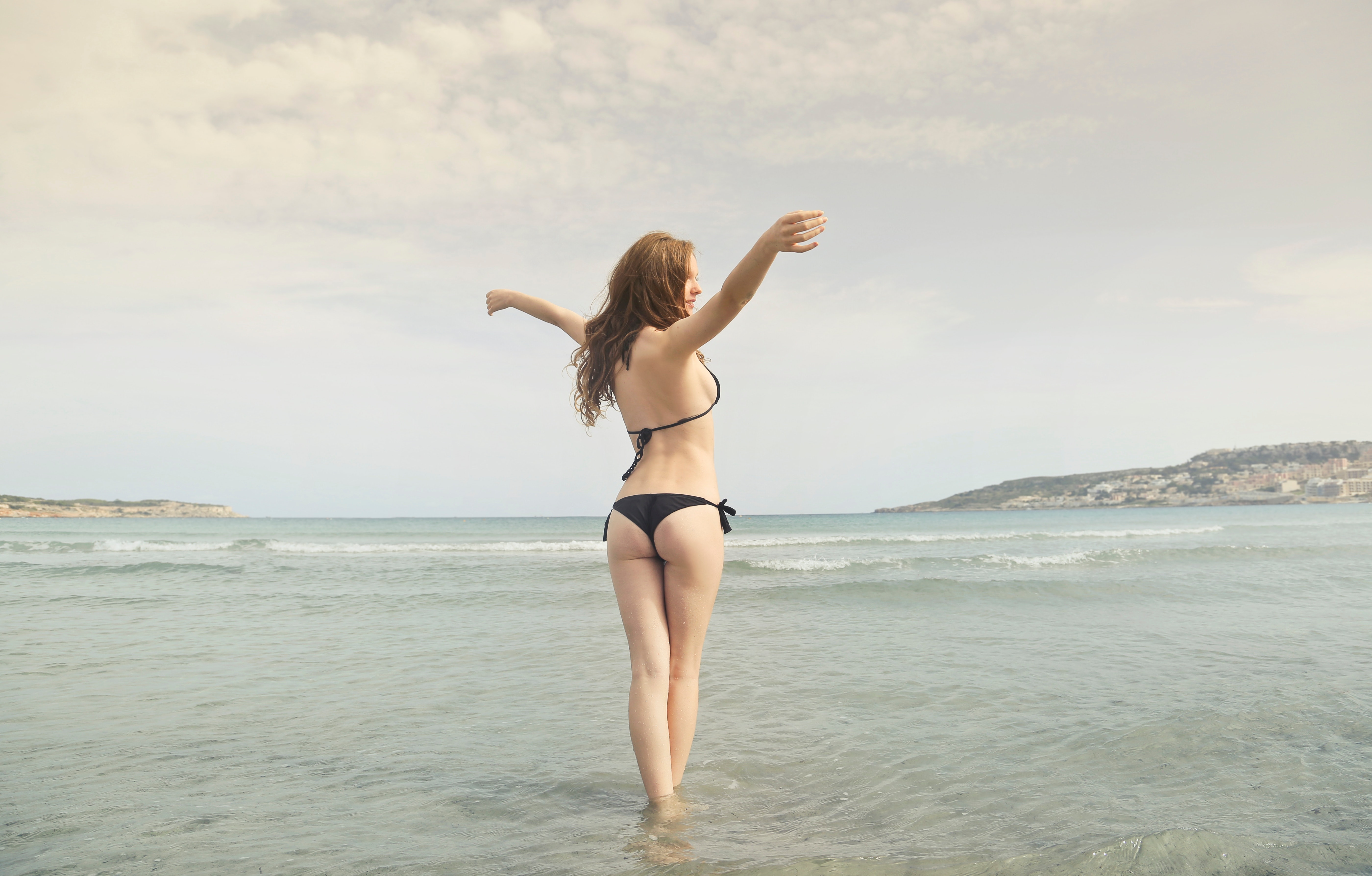 Woman in black bikini standing on shore photo