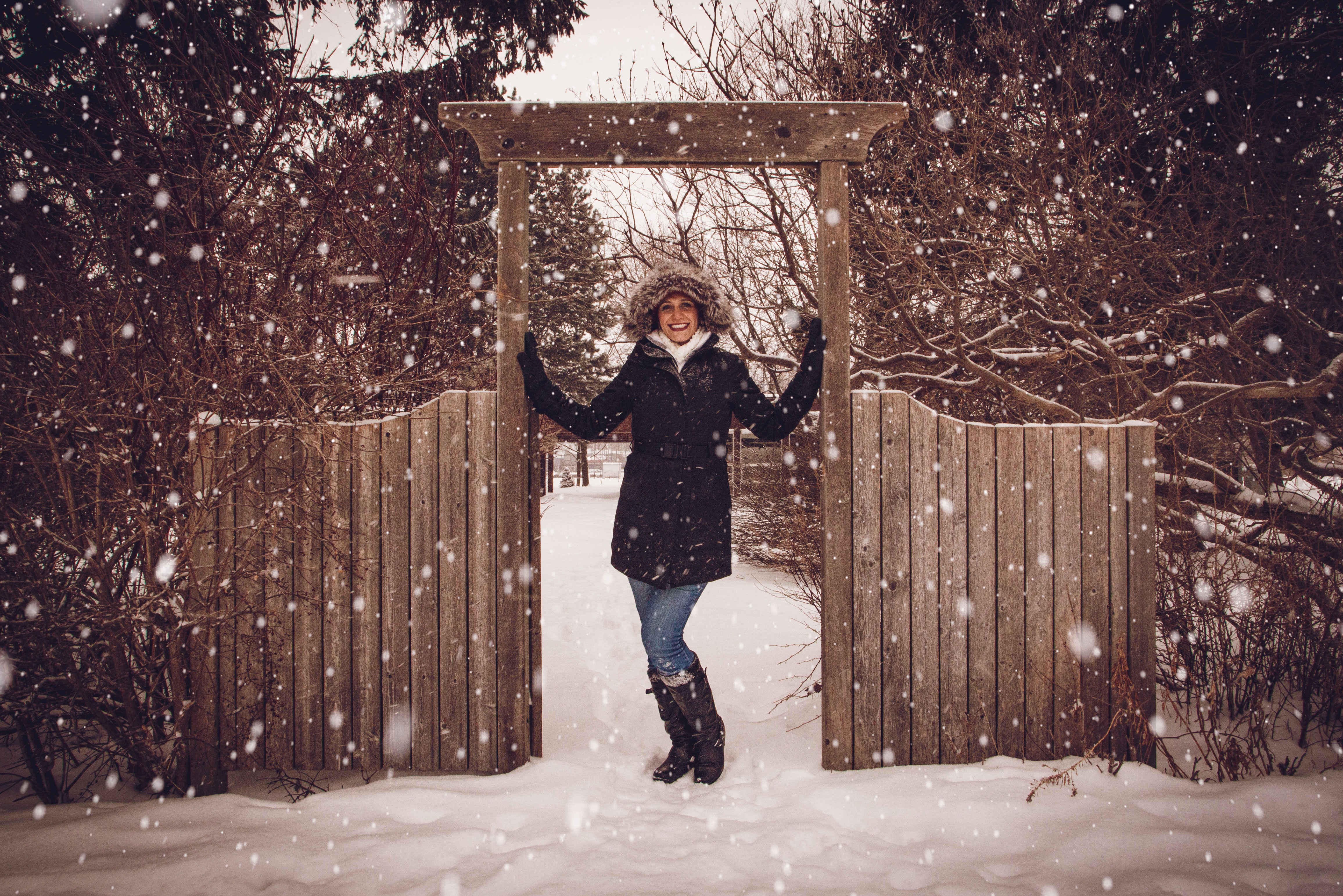 Woman in black coat beside fence during snow photo