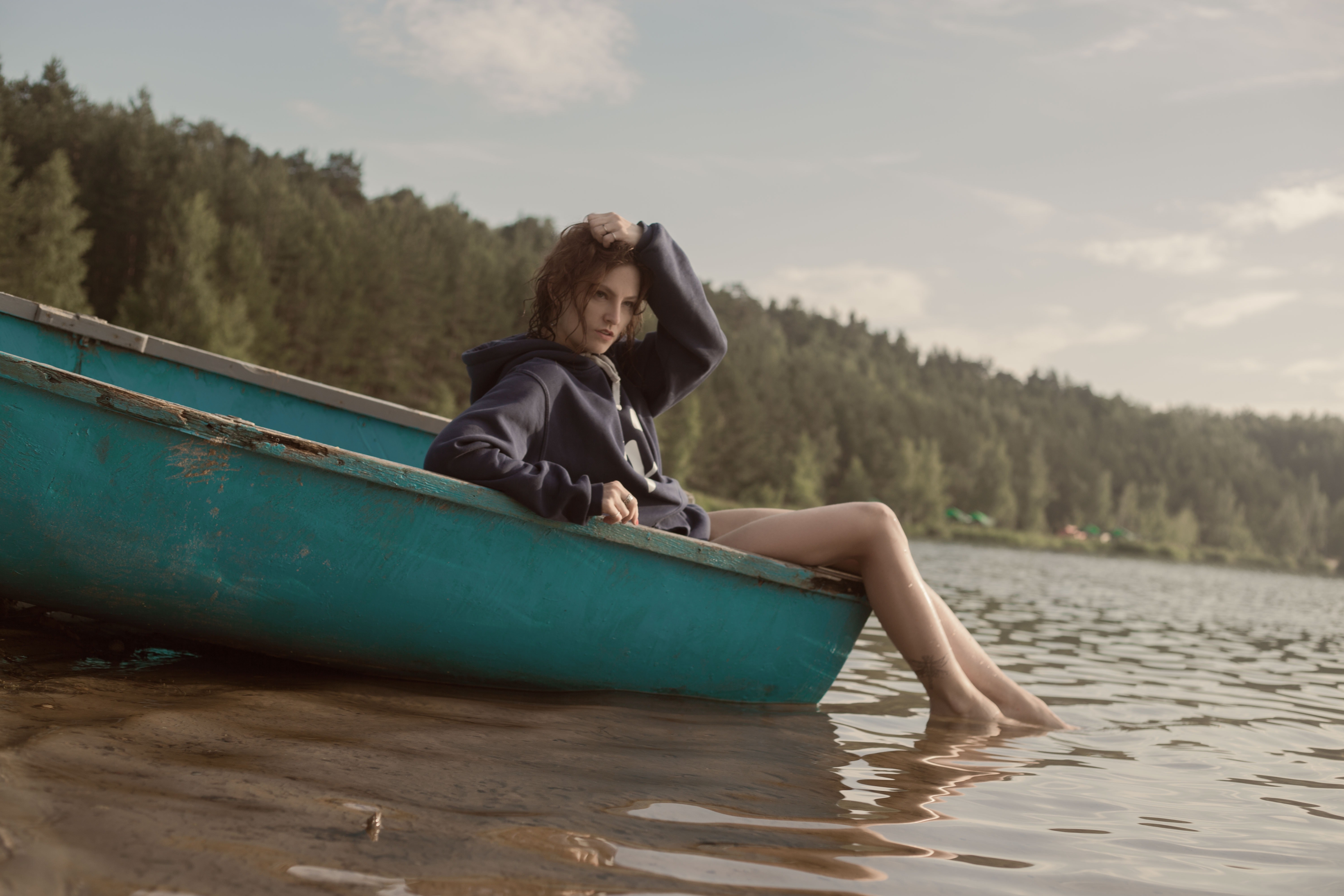 Woman in black hoodie in teal canoe in body of water photo
