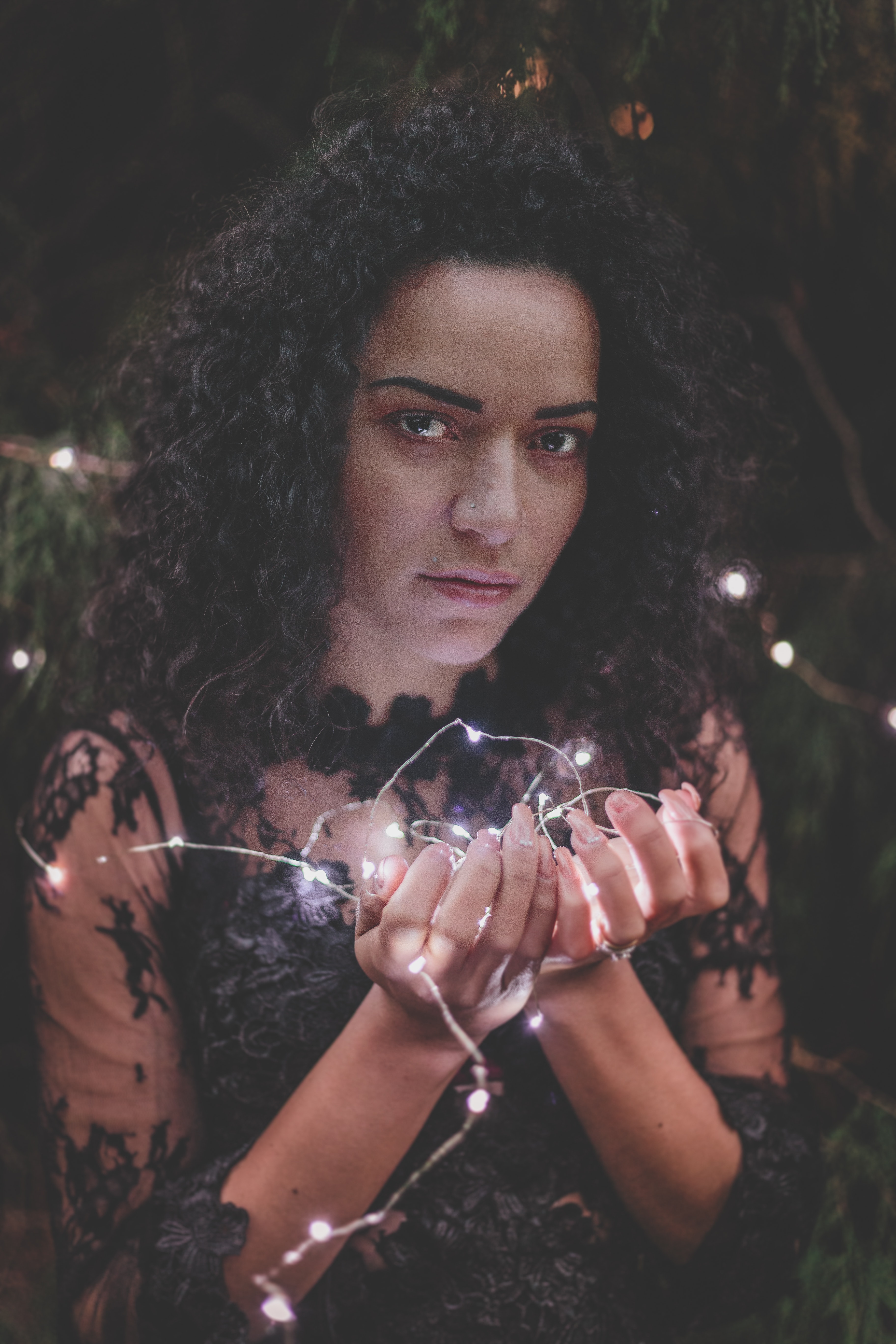 Woman in black lace dress holding string lights photo