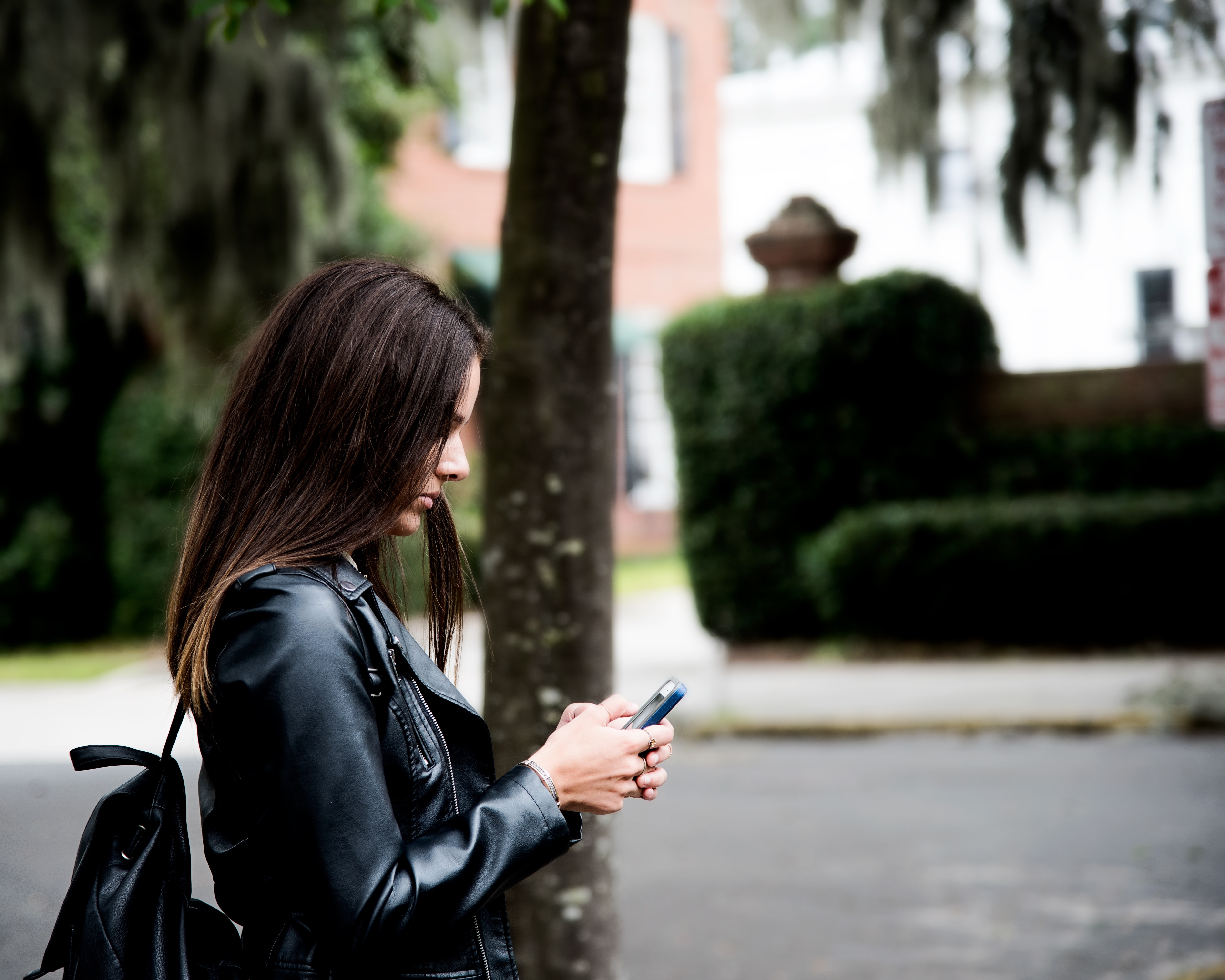 Woman in black leather jacket holding smartphone photo