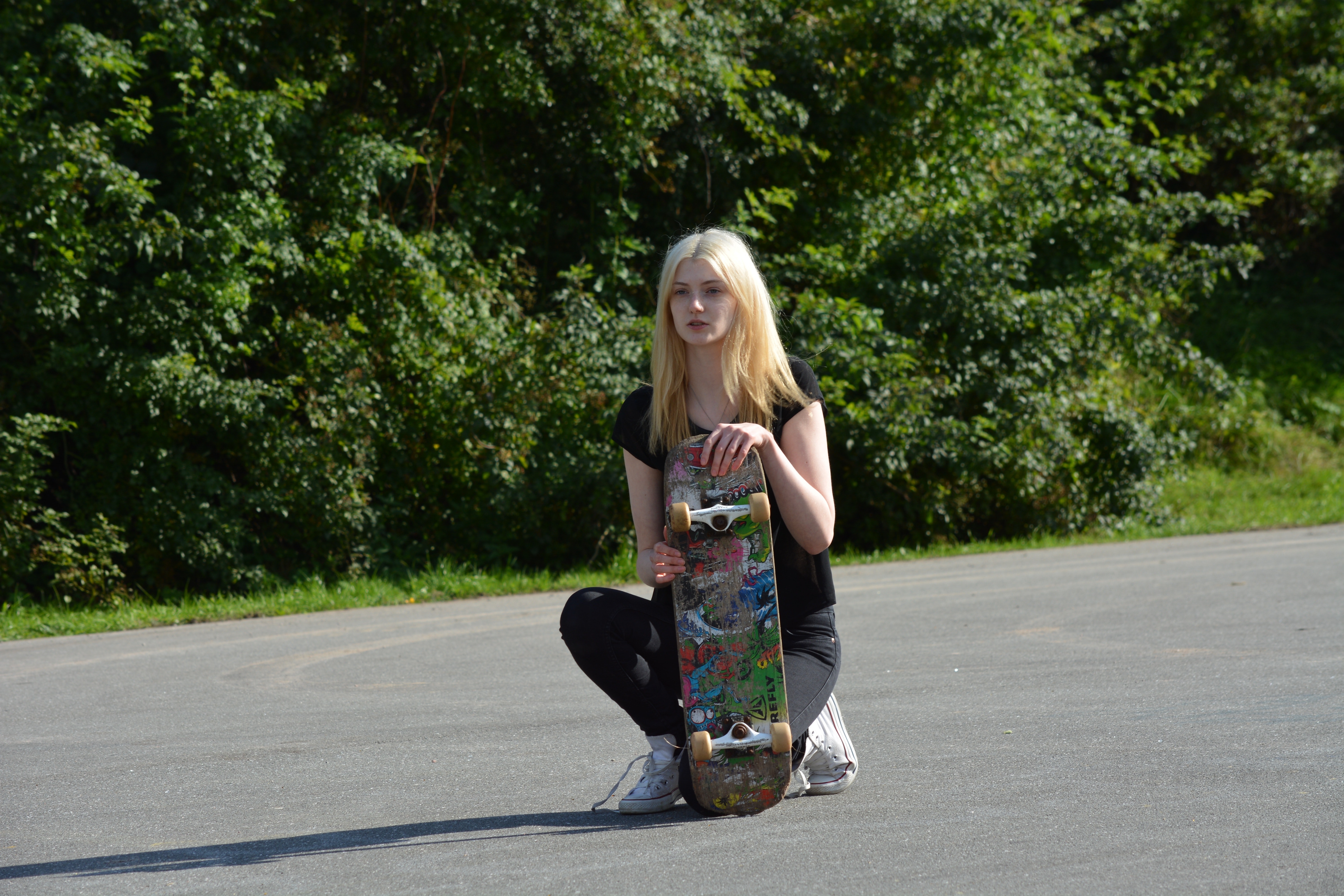 Woman in black shirt and pants holding skateboard during daytime photo