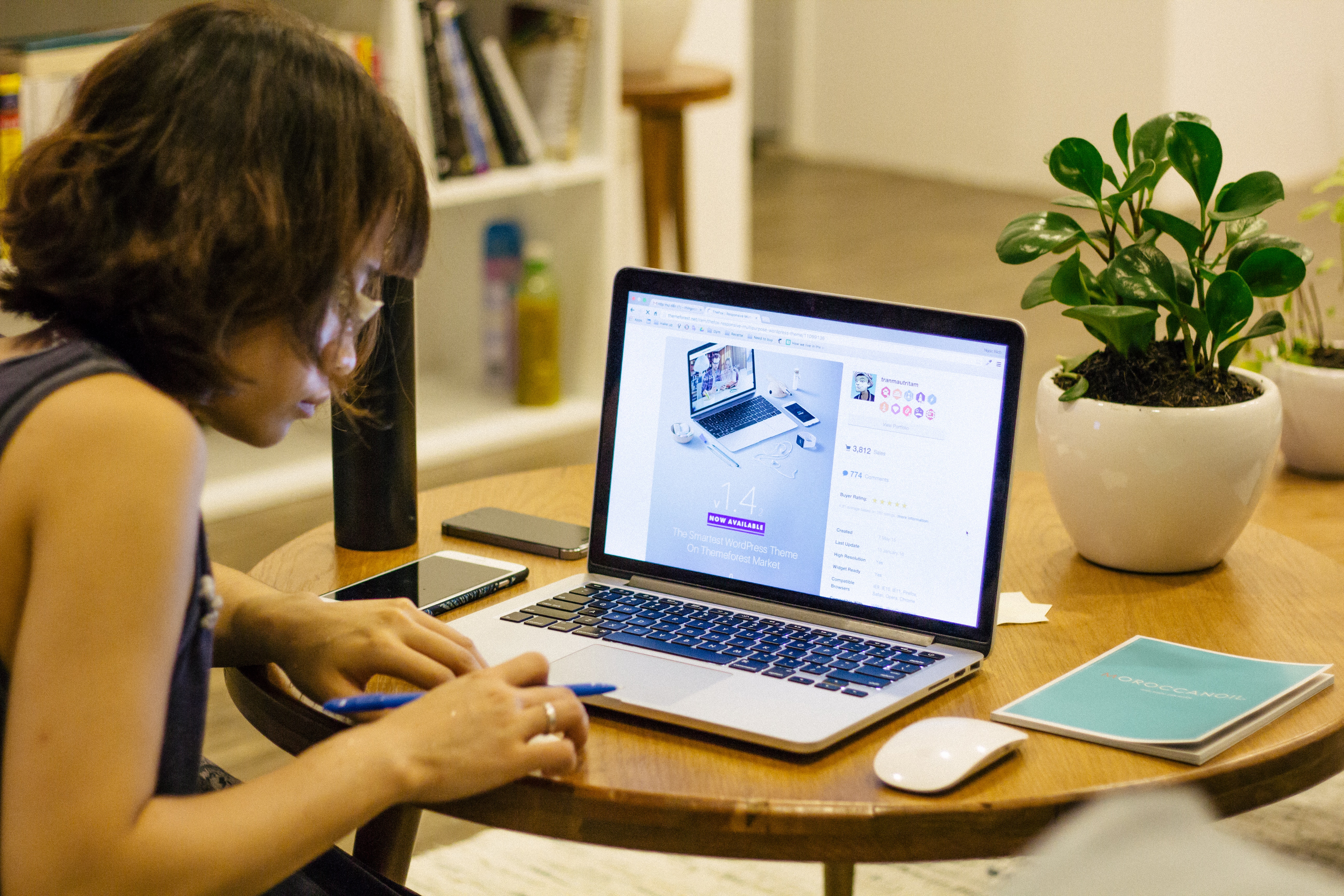 Woman in black tank shirt facing a black laptop computer on brown wooden round table photo