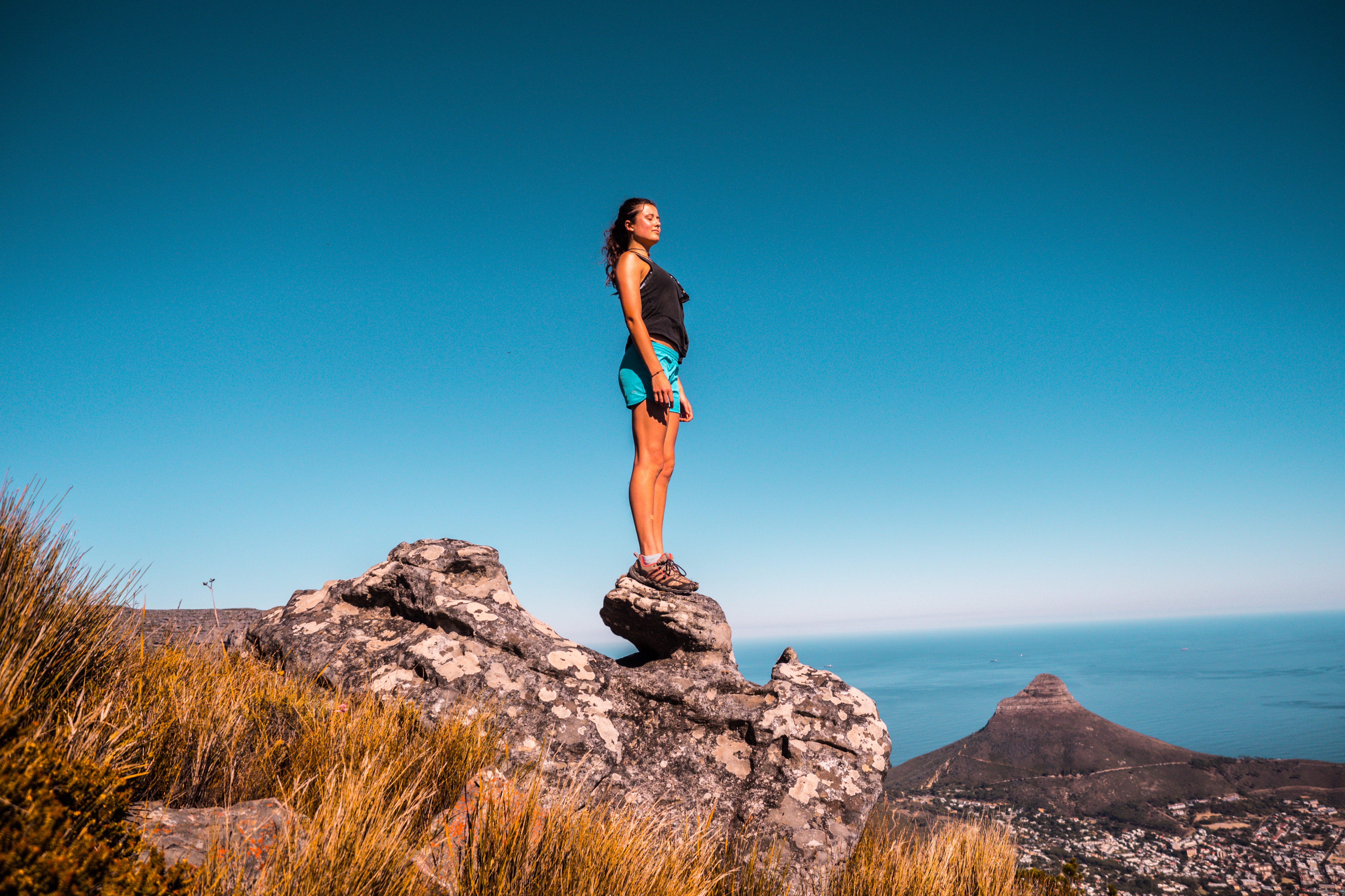 Woman in black top and blue shorts on stone under blue sky photo