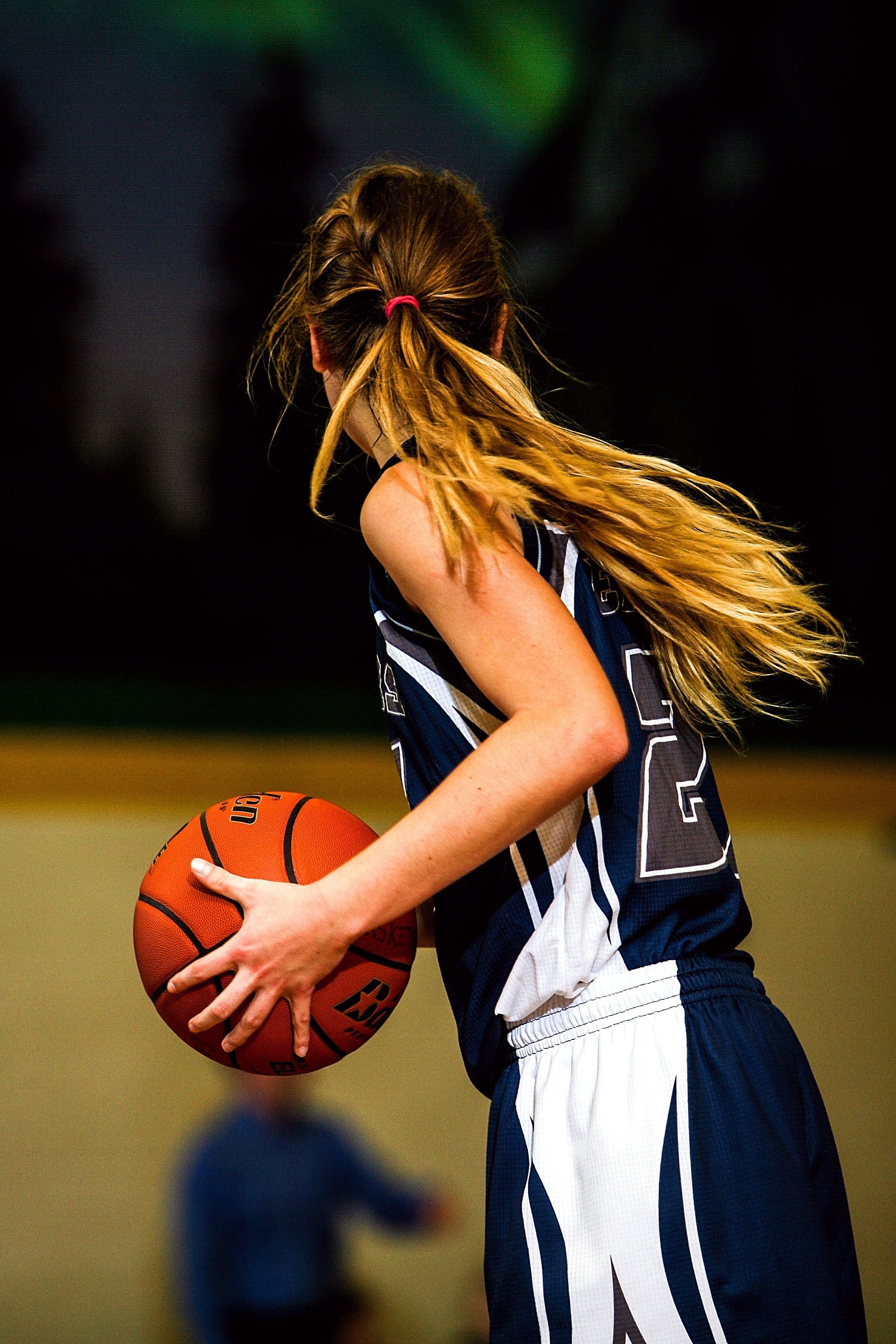 Woman in blue and white basketball jersey holding brown basketball photo