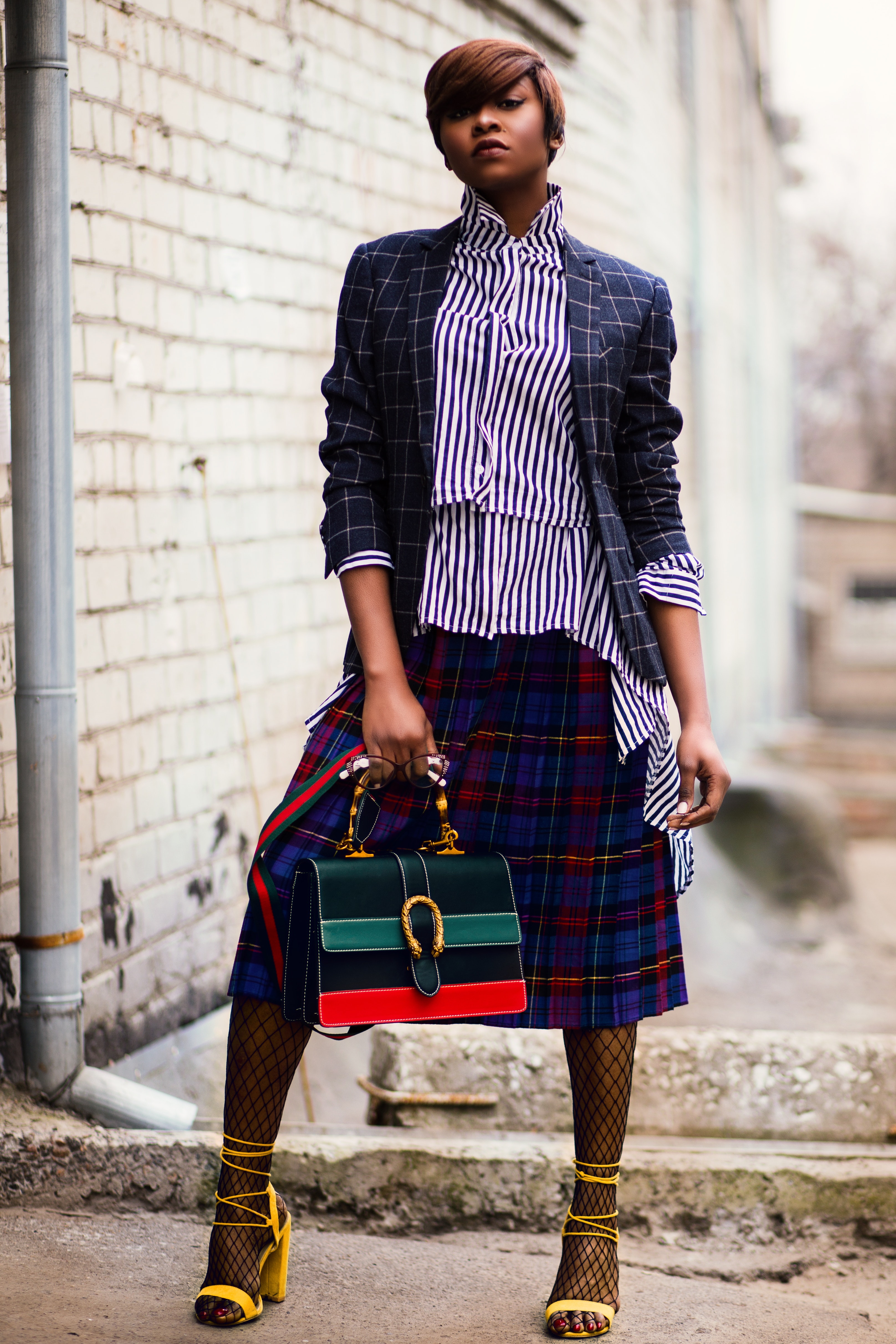 Woman in blue and white plaid cardigan holding green and red handbag photo