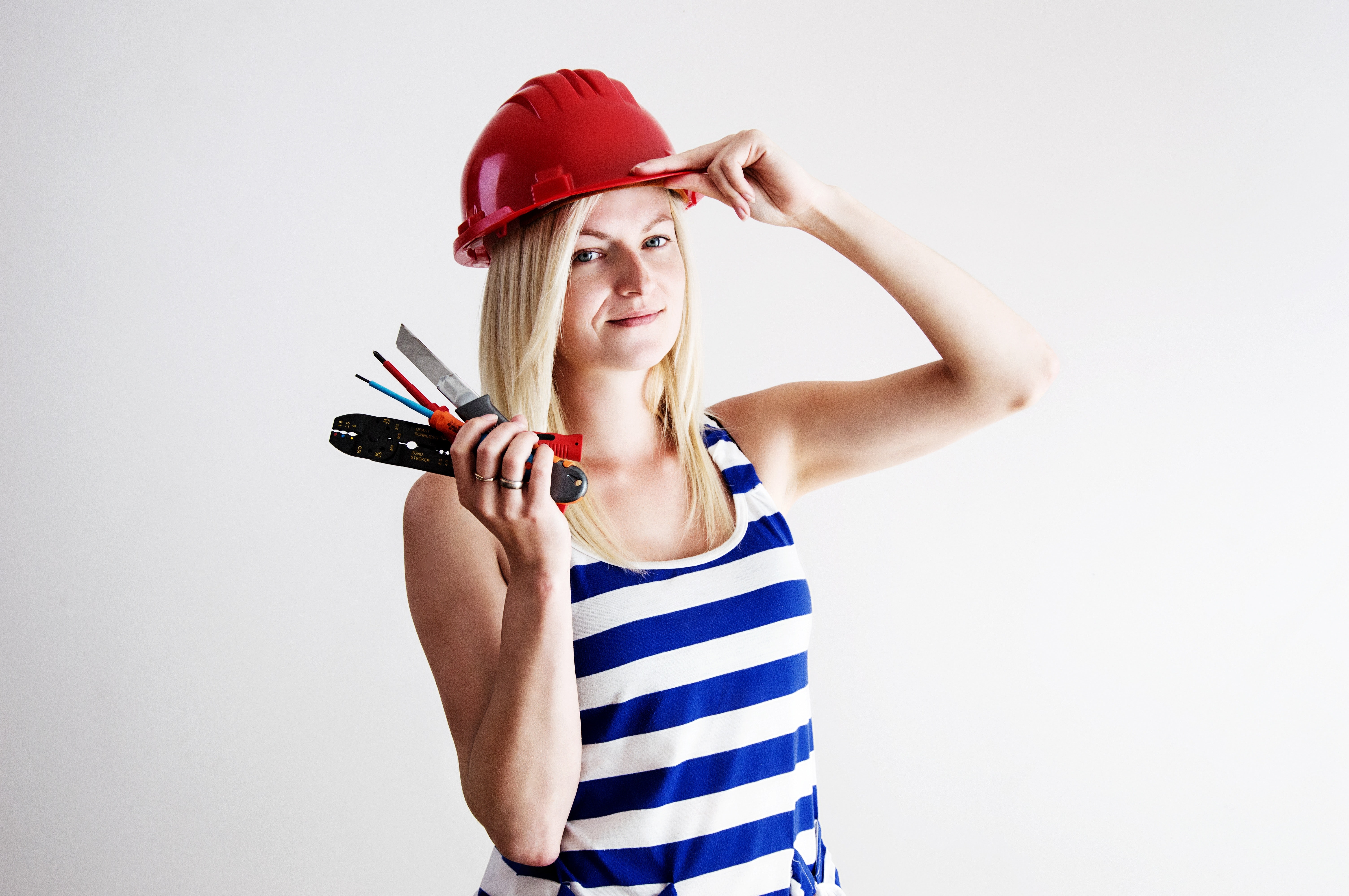 Woman in blue and white tank top wearing red hard hat photo
