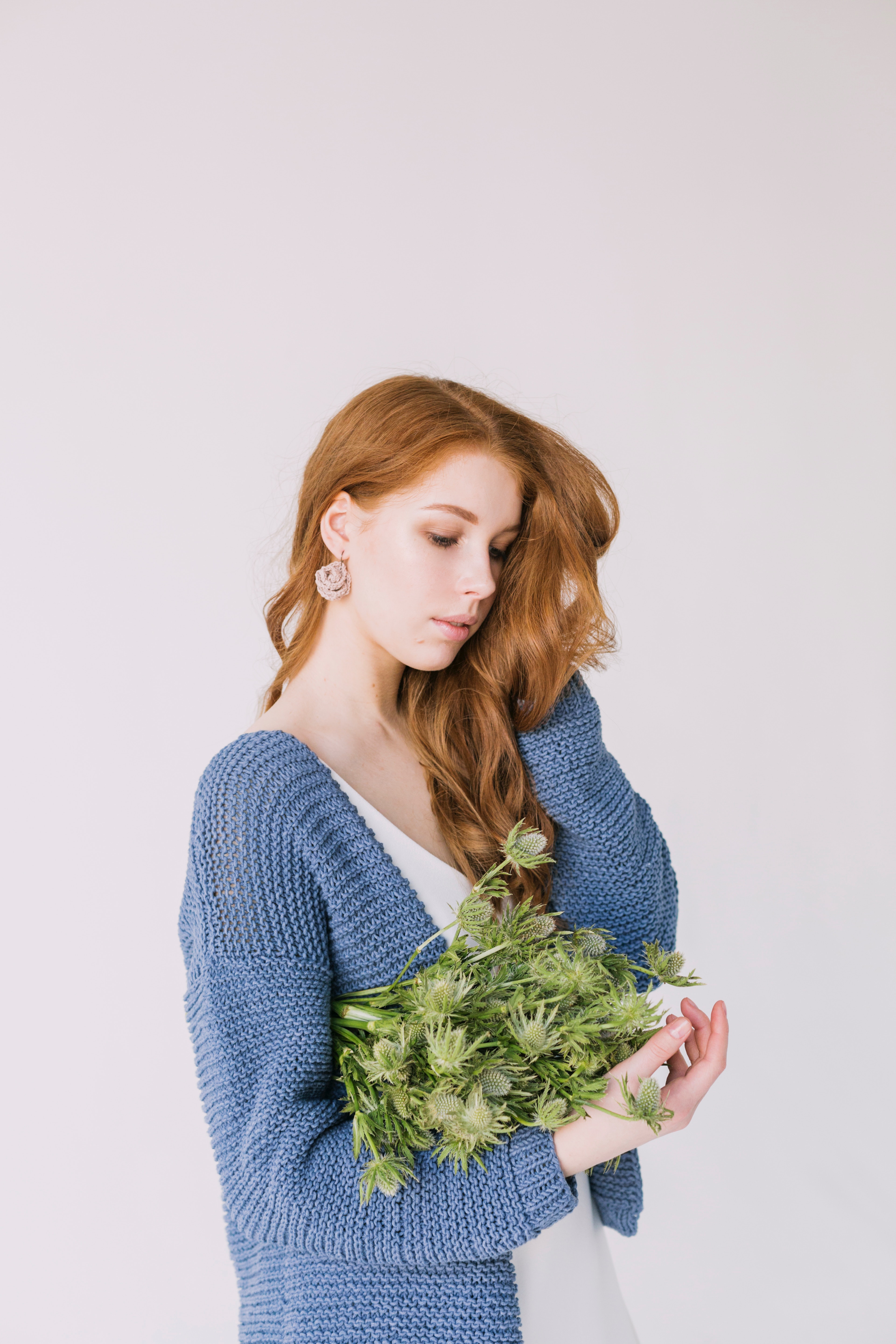 Woman in blue cardigan holding green flowers photo