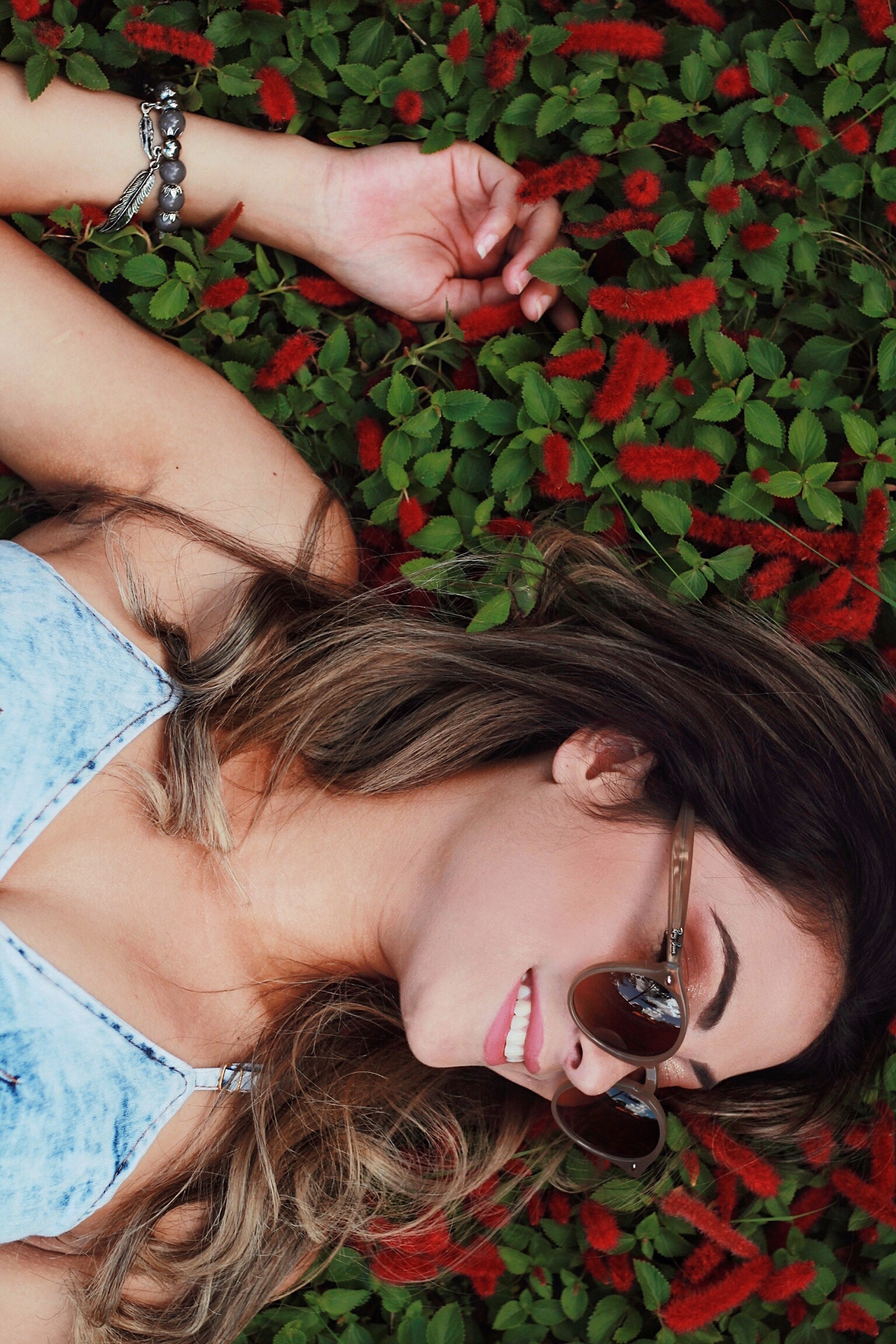 Woman in blue chambray spaghetti strap dress wearing sunglasses with red flower background photo