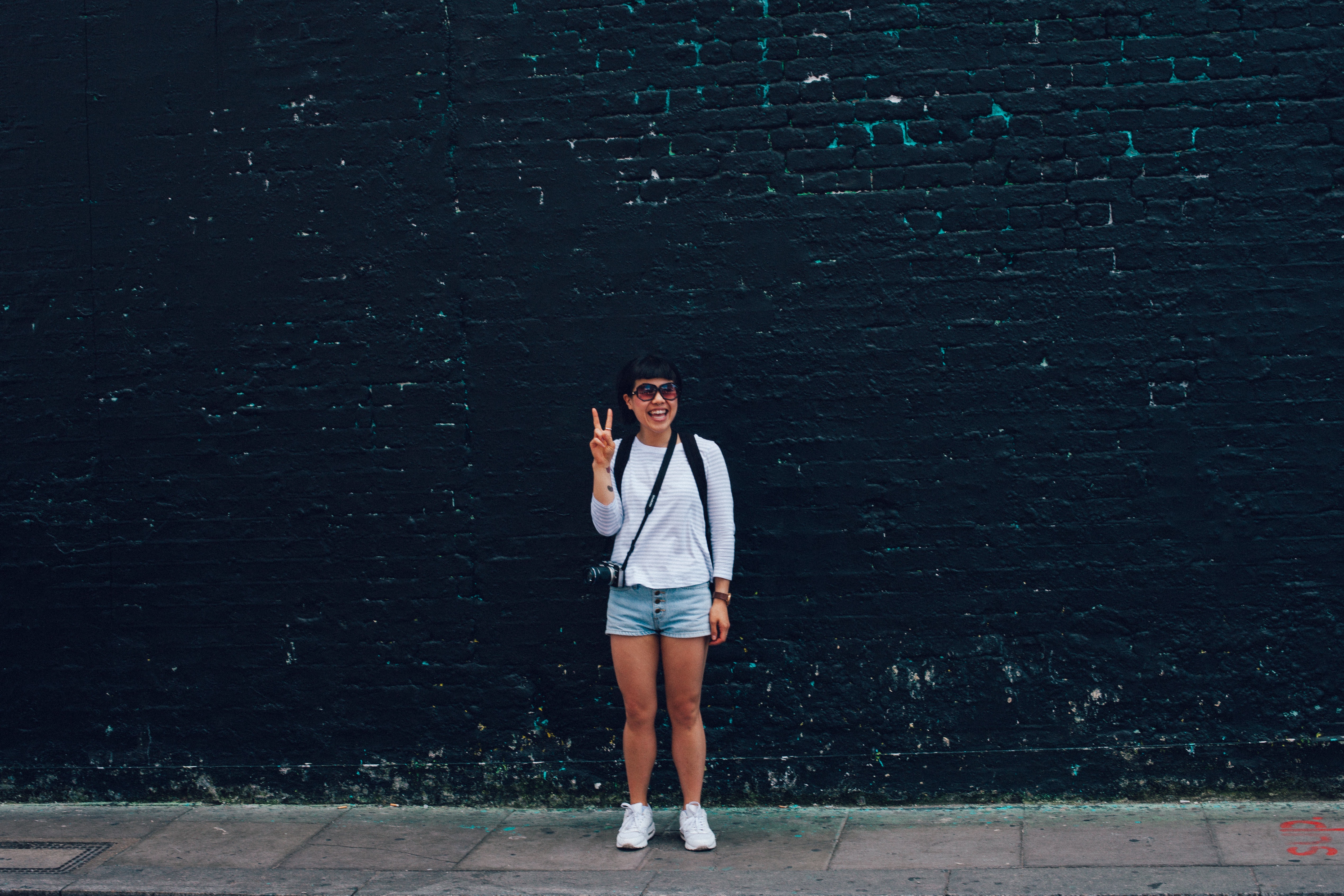 Woman in blue denim shorts standing in front of black brick wall photo