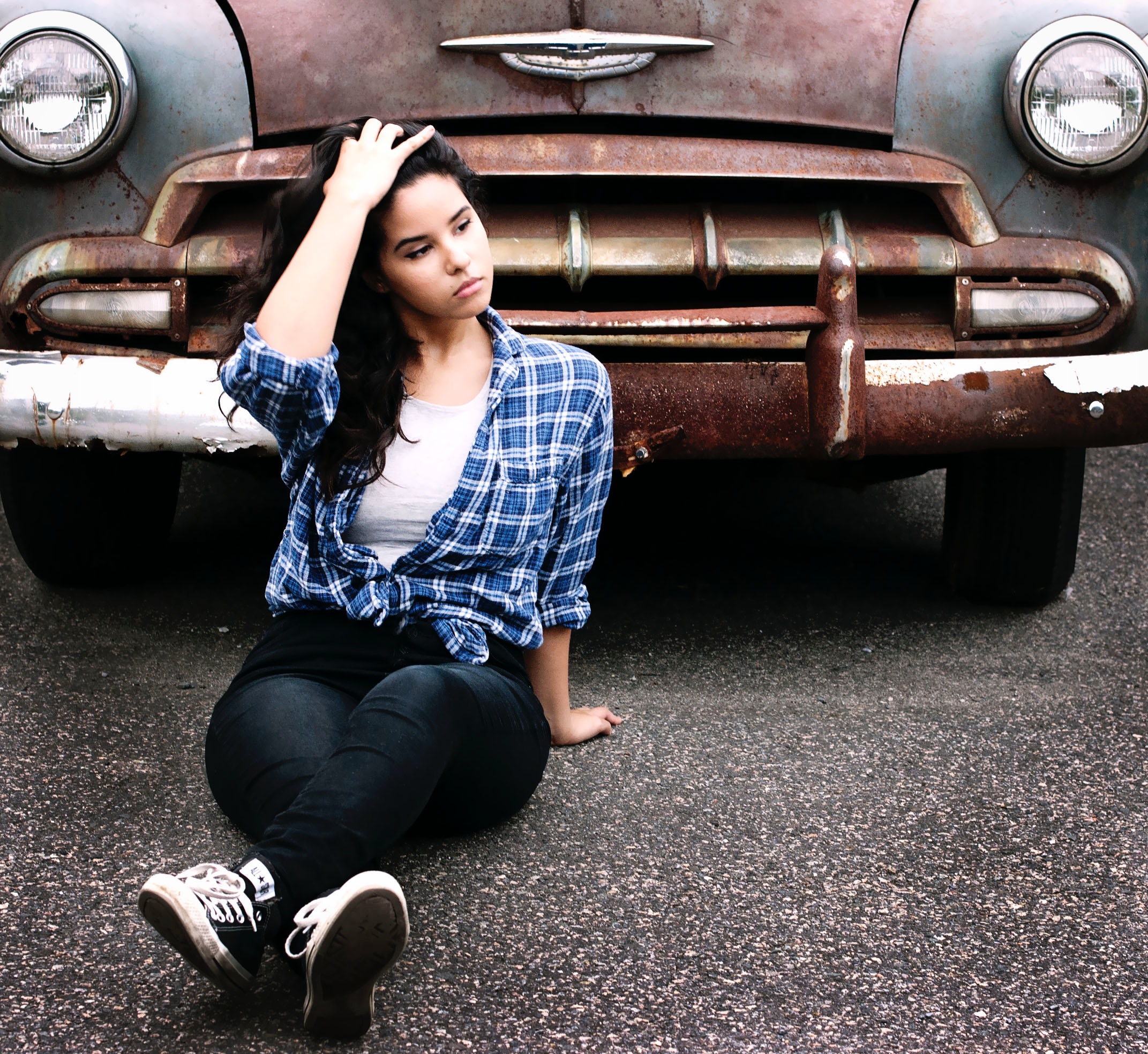 Woman in blue sports shirt sitting infront of vintage brown car photo