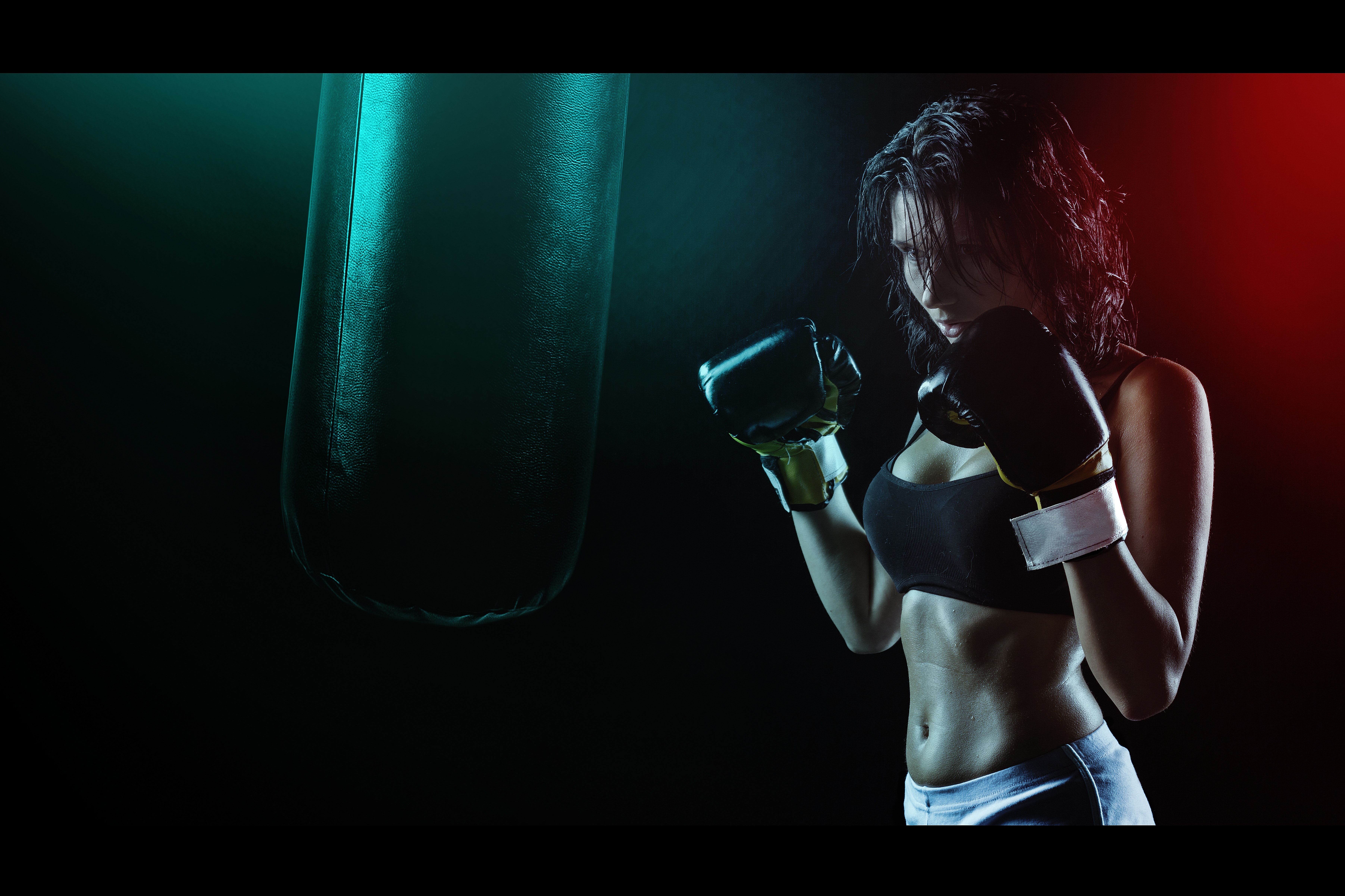 Woman in boxing gloves with sports bra posing boxing style in front of punching bag photo
