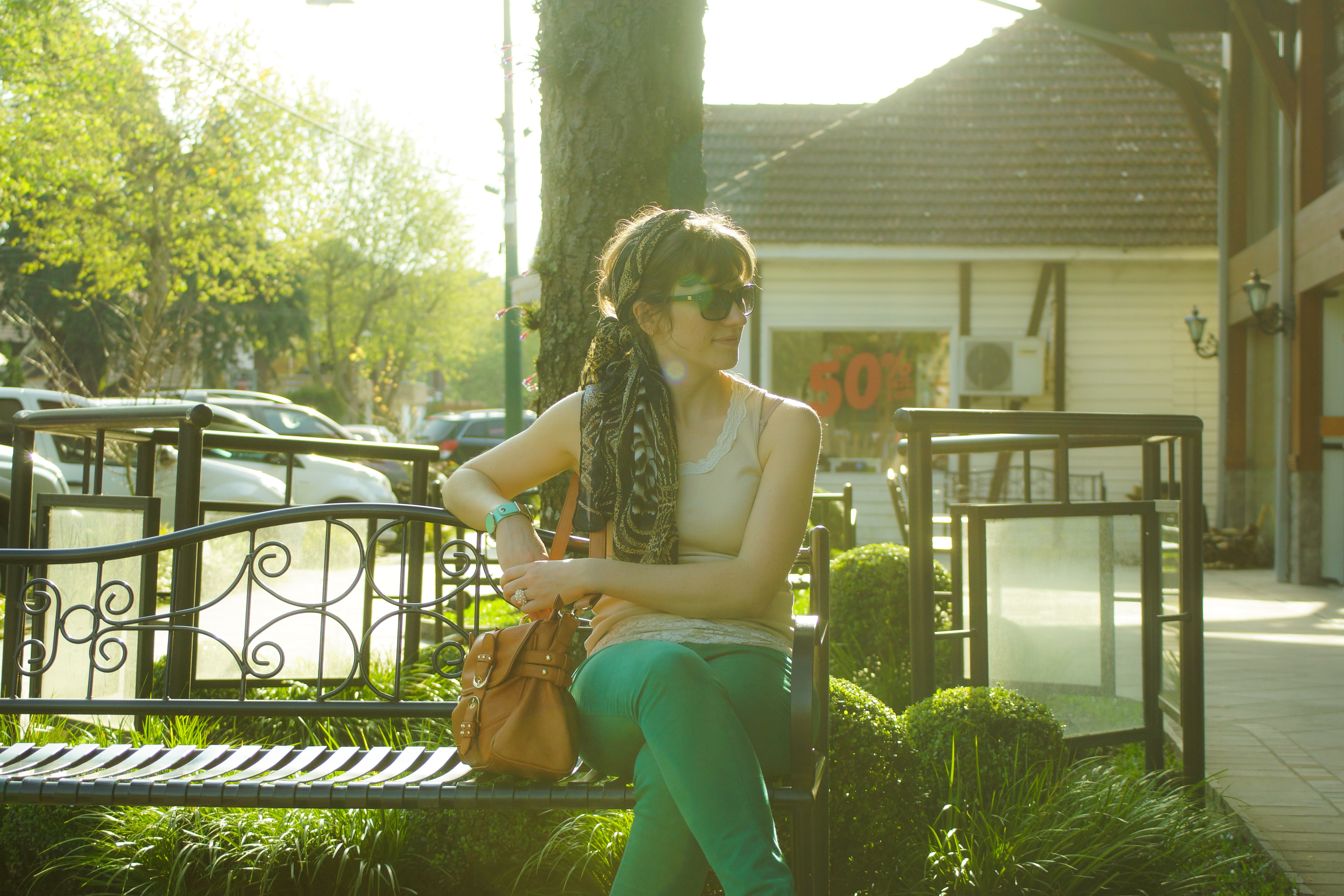 Woman in brown tank top sitting on black bench beside tree photo