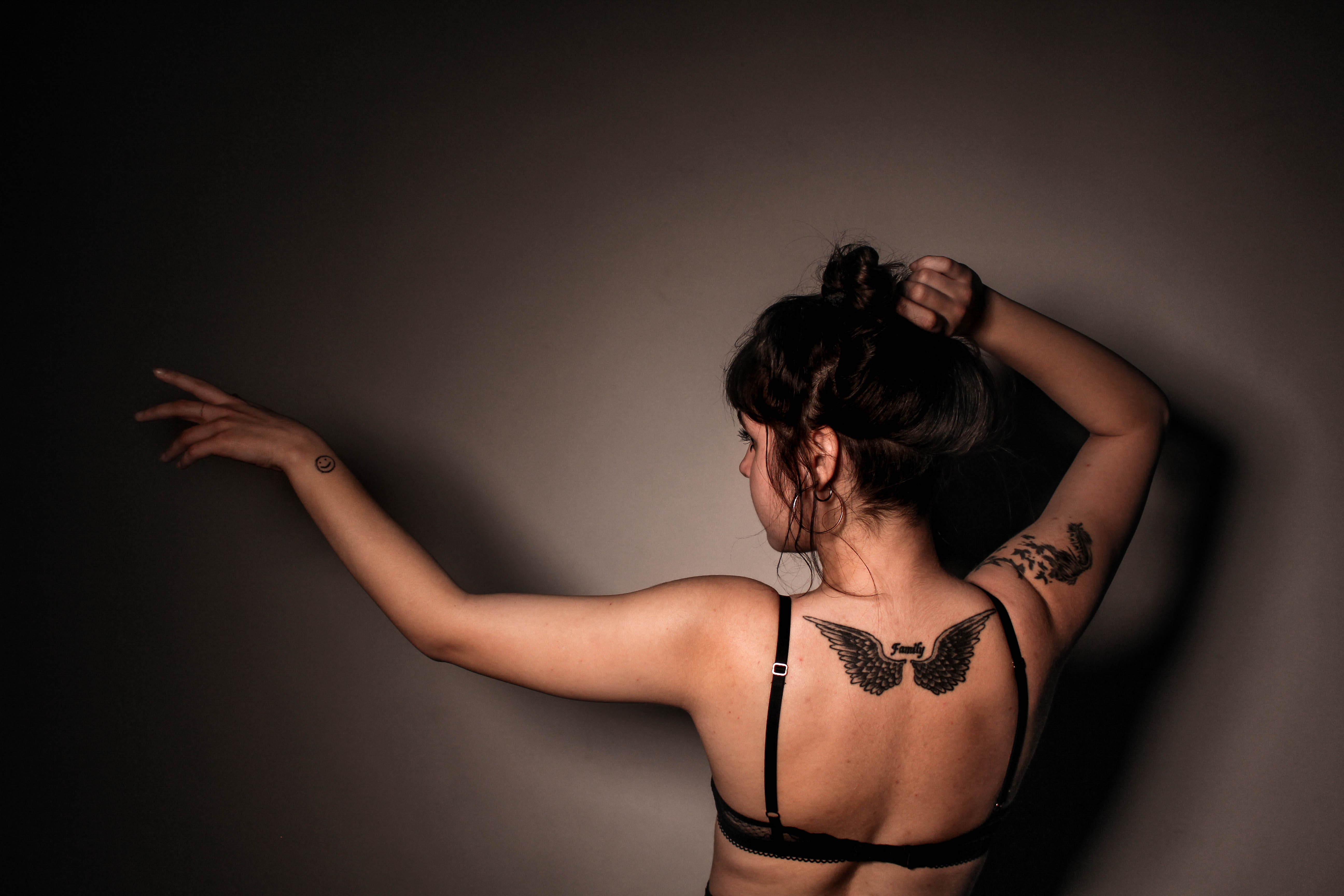 Woman in eagle tattoo in back wearing black bra photo