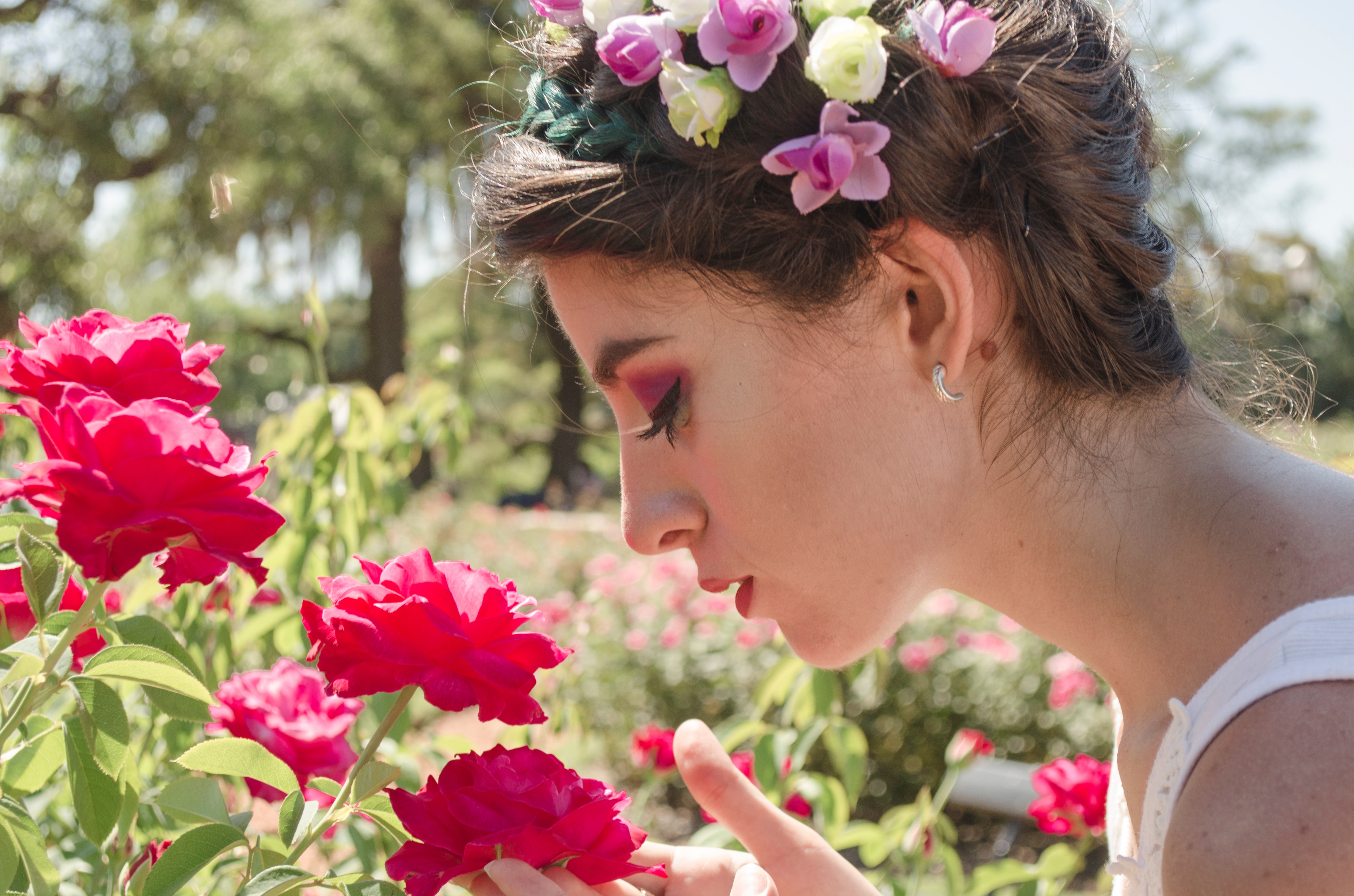Woman in floral headdress sniffing on red flowers photo