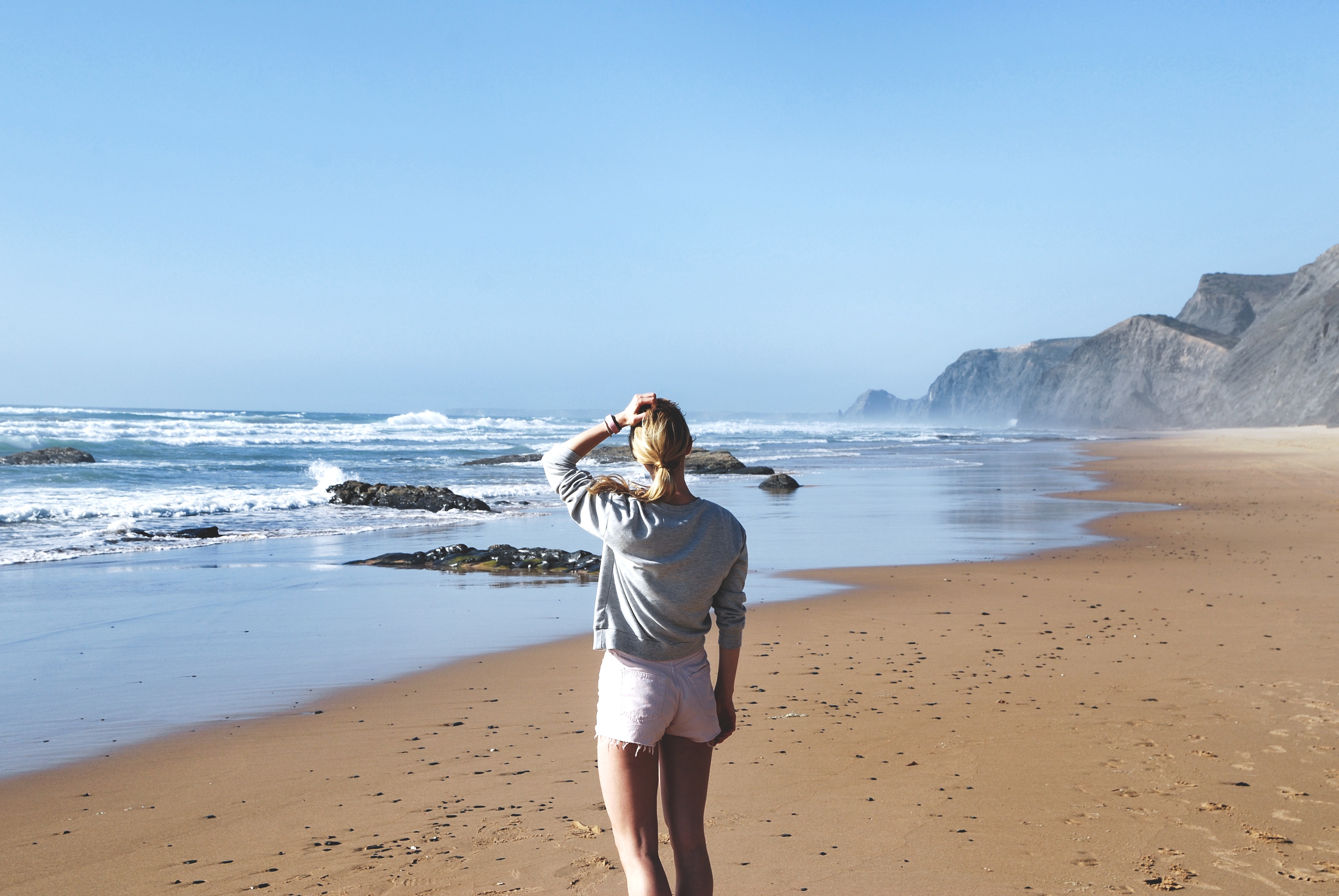 Woman in gray long-sleeved shirt with pink short shorts standing near sea photo