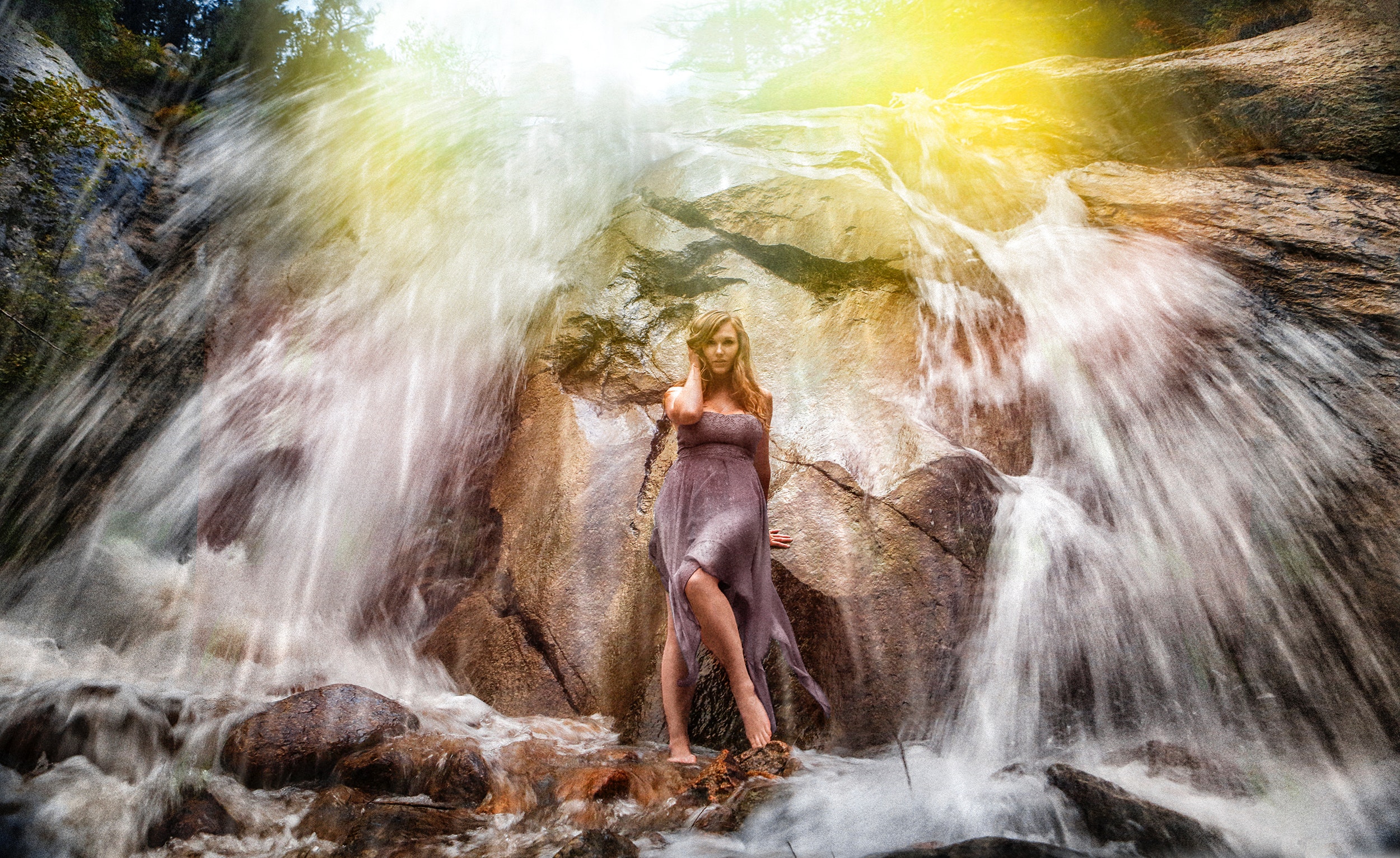 Woman in gray strapless long dress standing under waterfalls photo