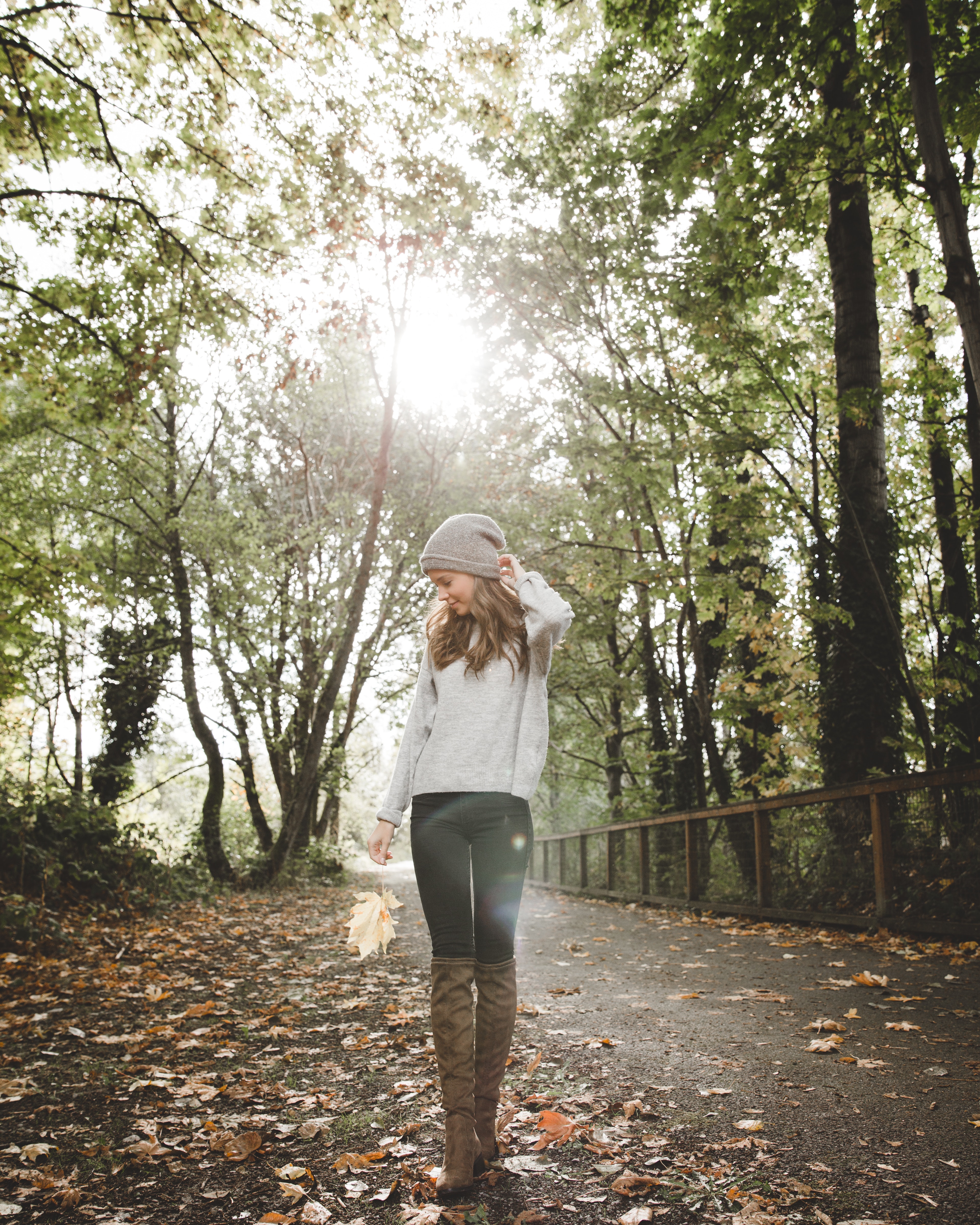 Woman in gray sweater standing between forest trees photo