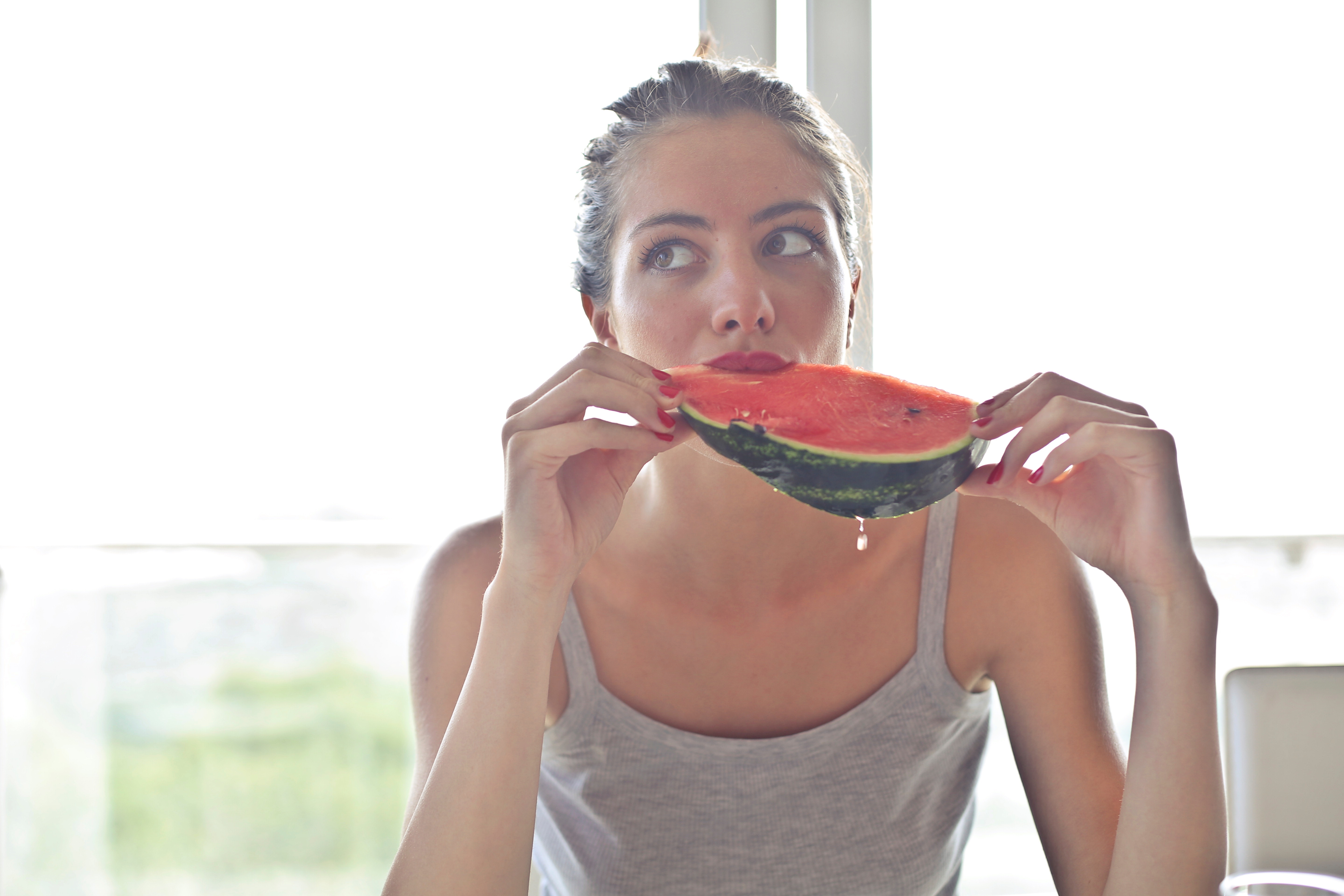 Woman in gray tank top holding watermelon photo
