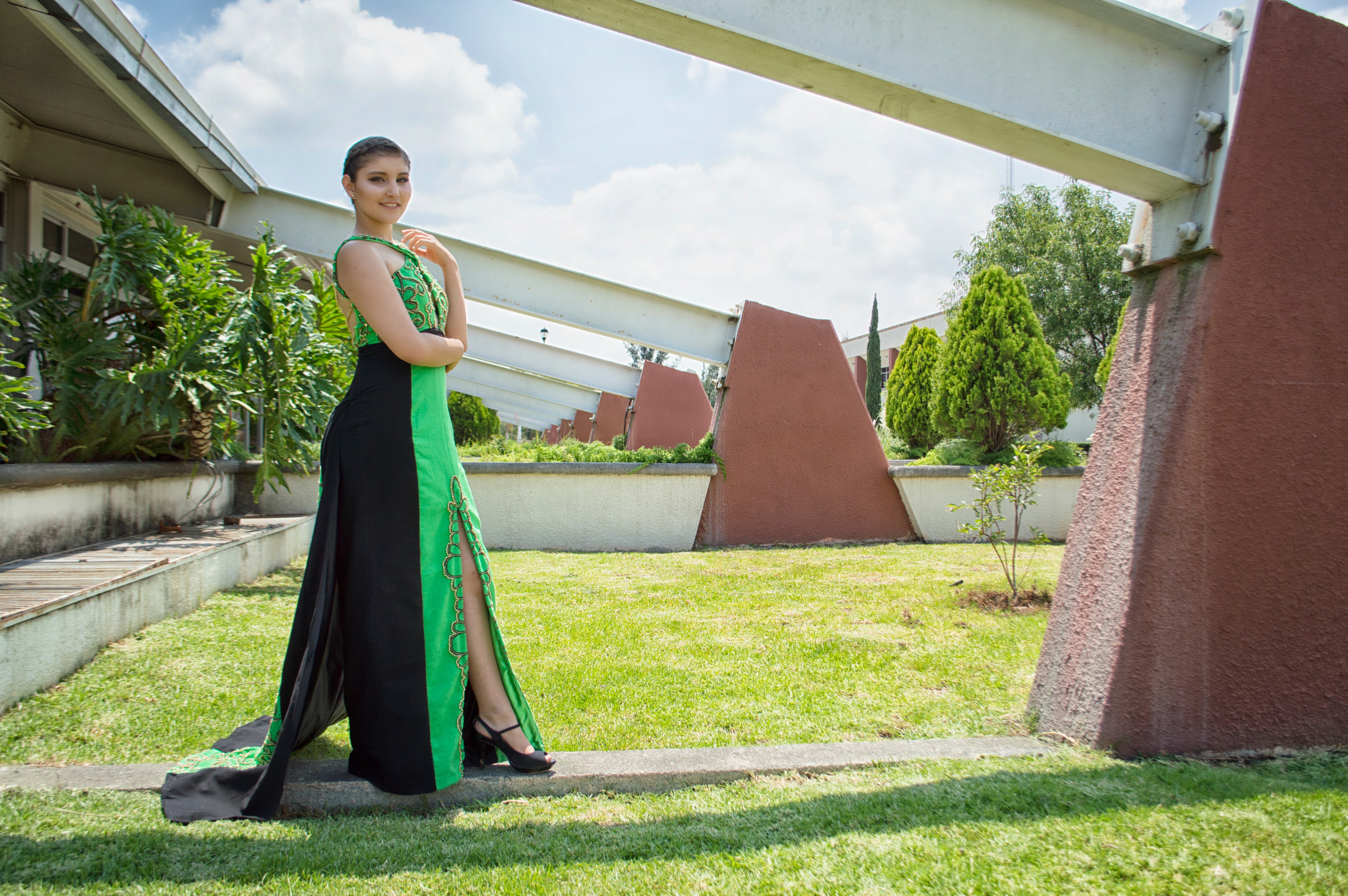 Woman in green and black dress standing in front of wall photo