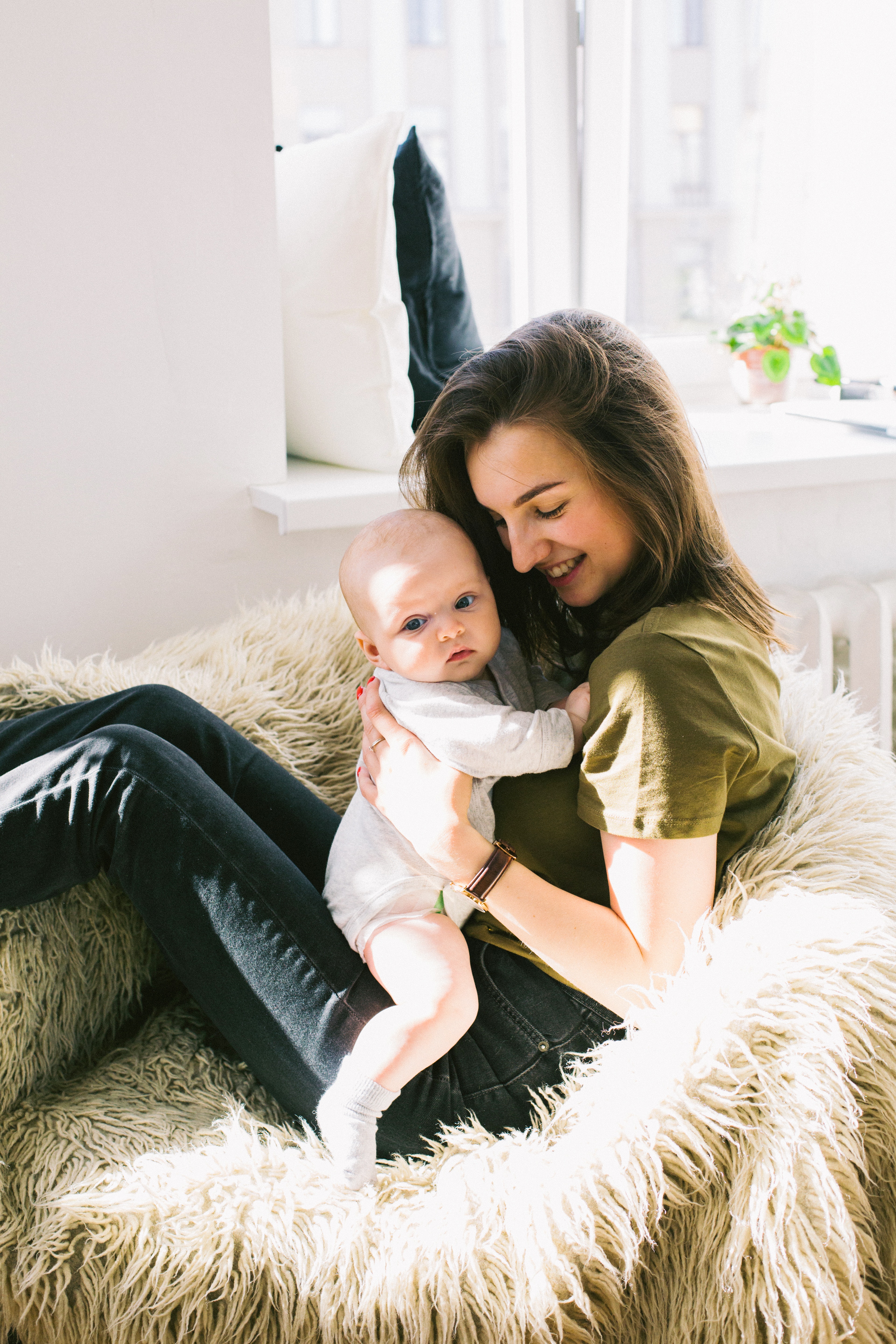 Woman in green shirt holding baby while sitting photo