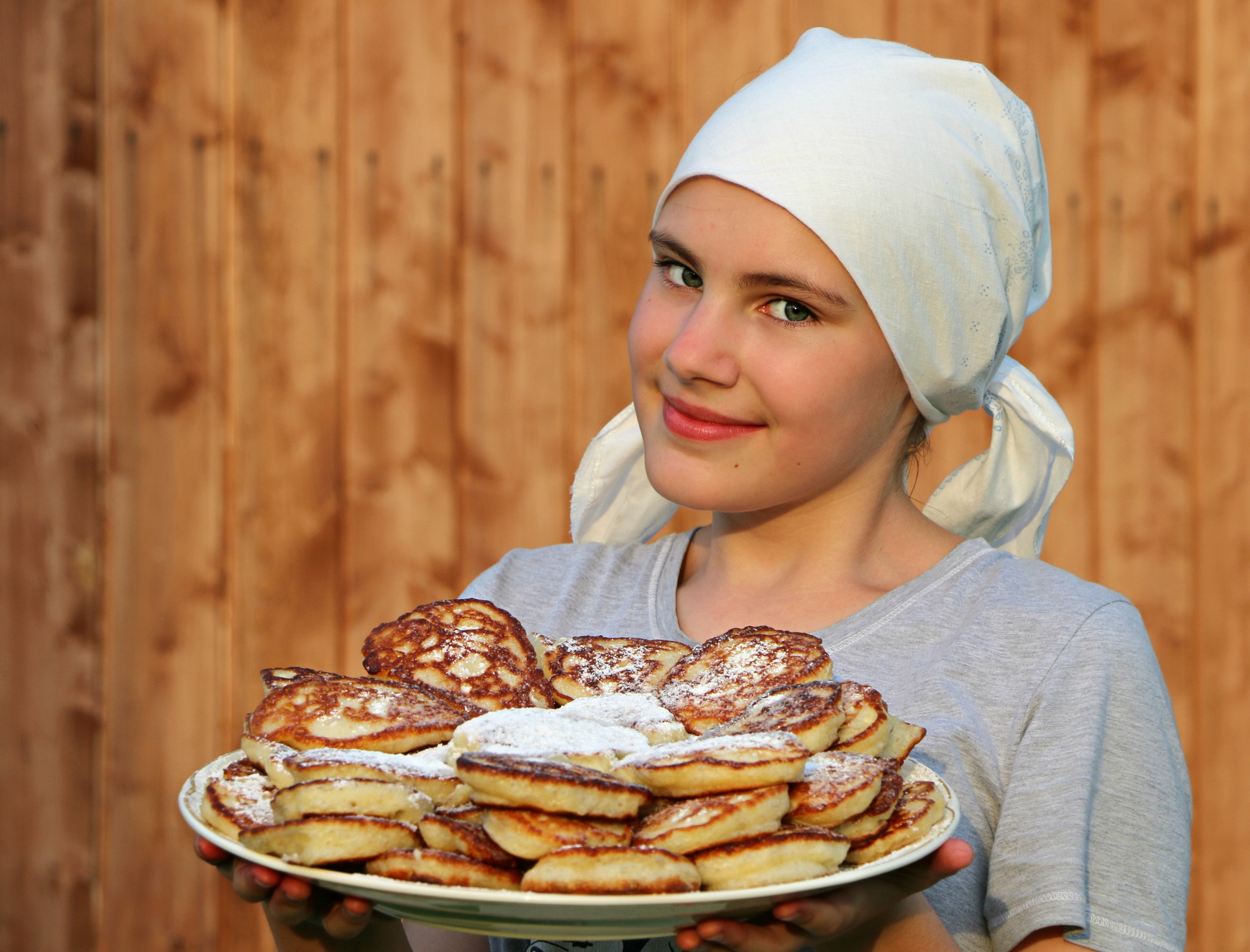 Woman in grey crew neck shirt holding a white ceramic plate with pancakes photo