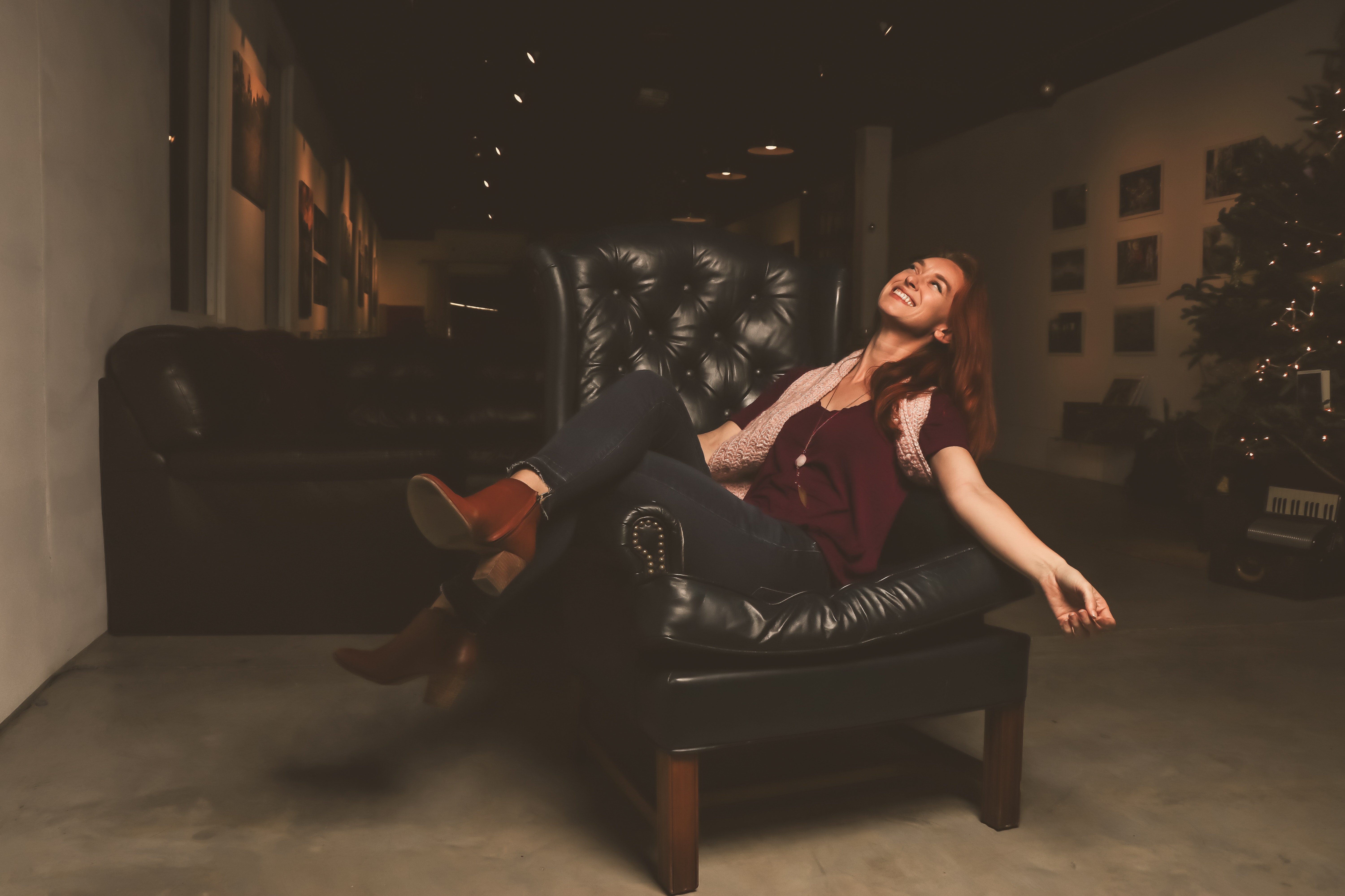 Woman in maroon scoop-neck shirt sitting on black leather sofa chair photo