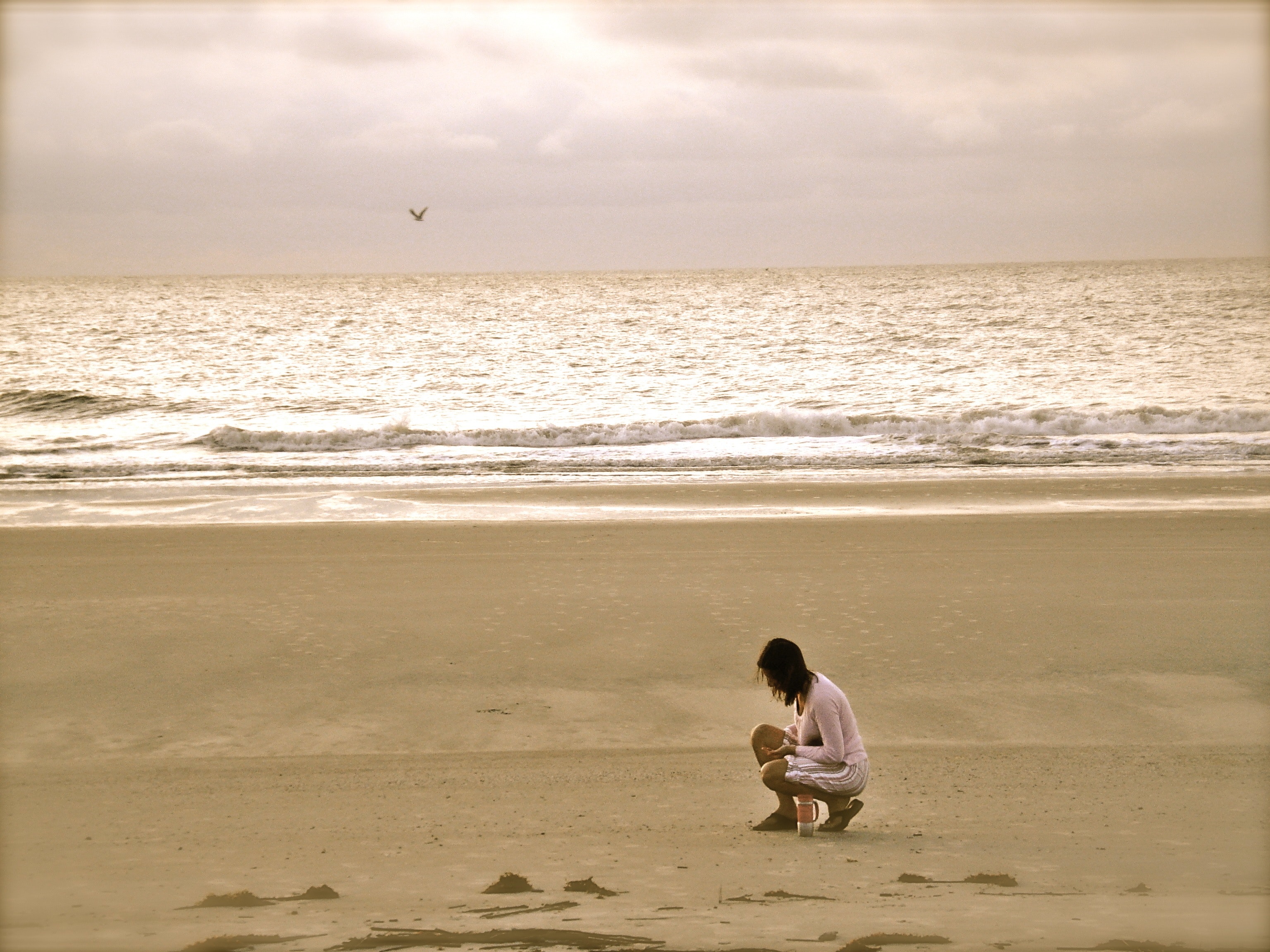 Woman in pink cardigan sitting on seashore photo