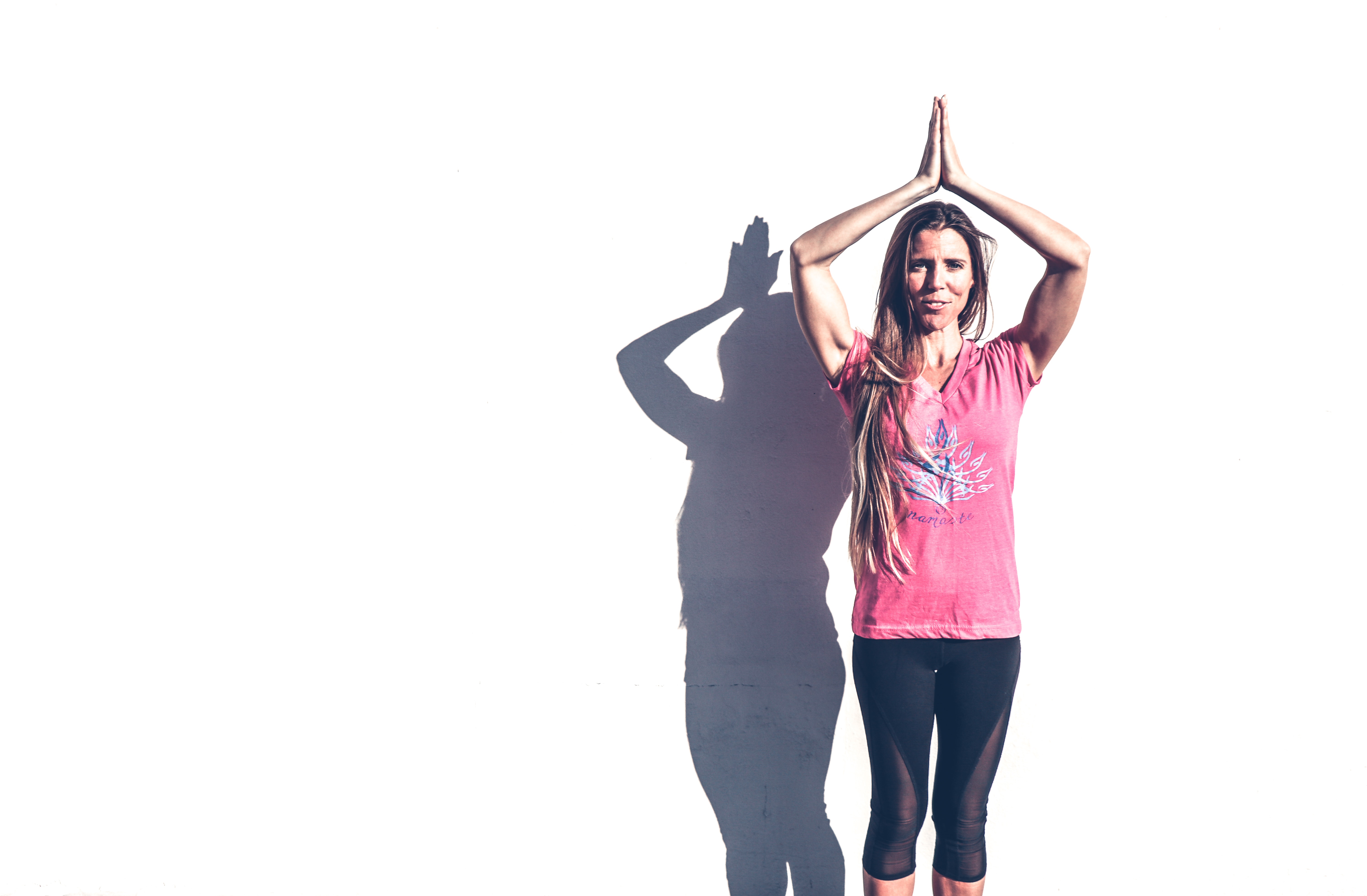 Woman in pink crew-neck t-shirt and black leggings standing near white wall photo