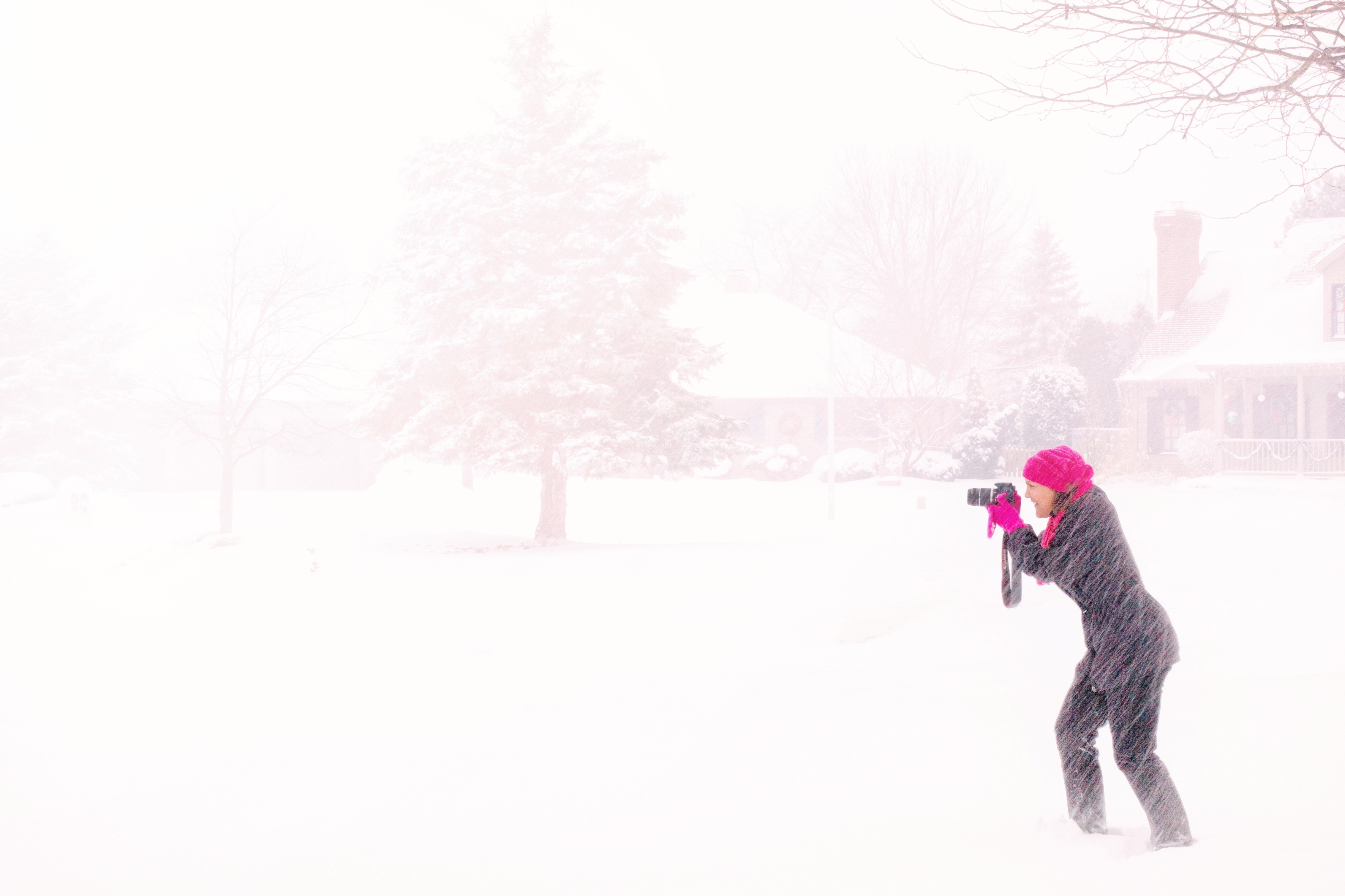 Woman in pink hijab holding black dslr camera under raging snow during daytime photo