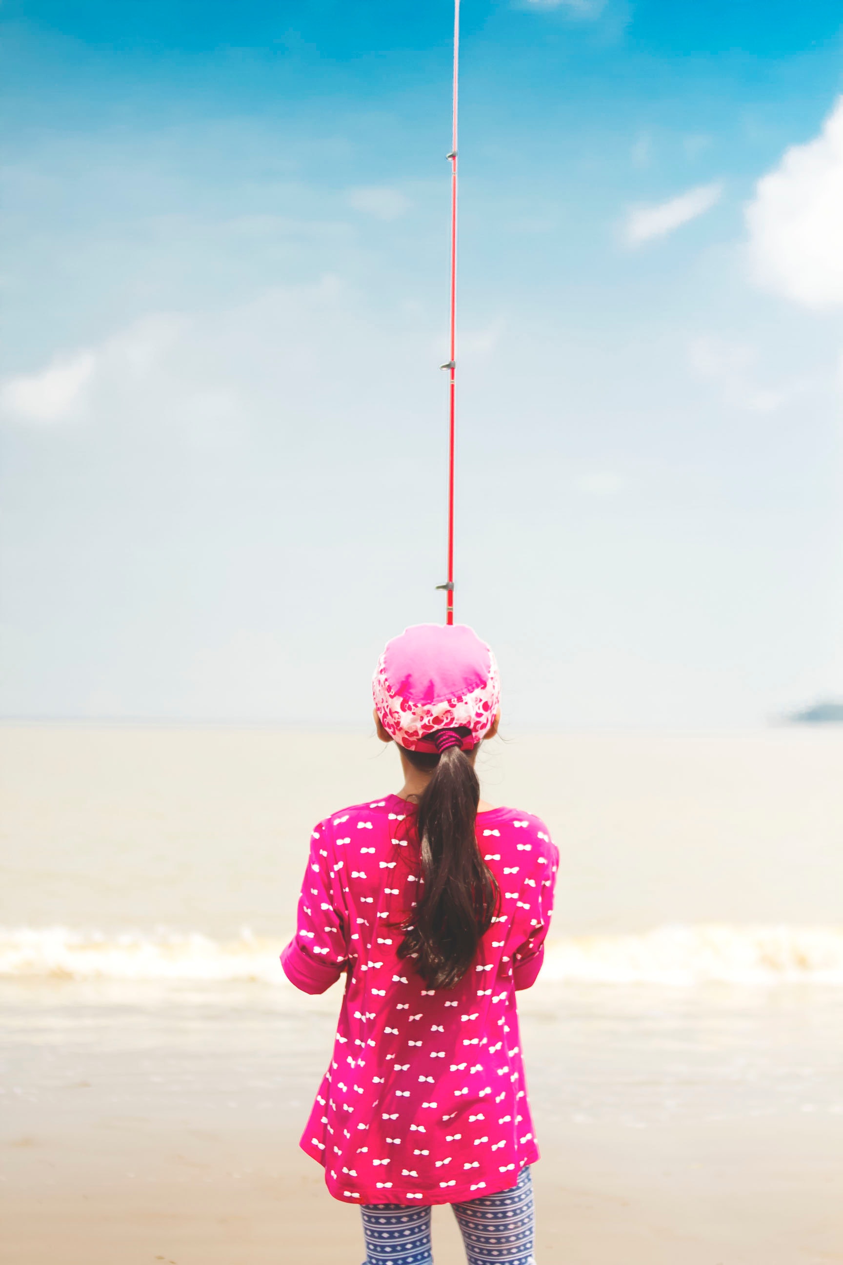 Woman in pink long-sleeved shirt holding red fishing rod photo