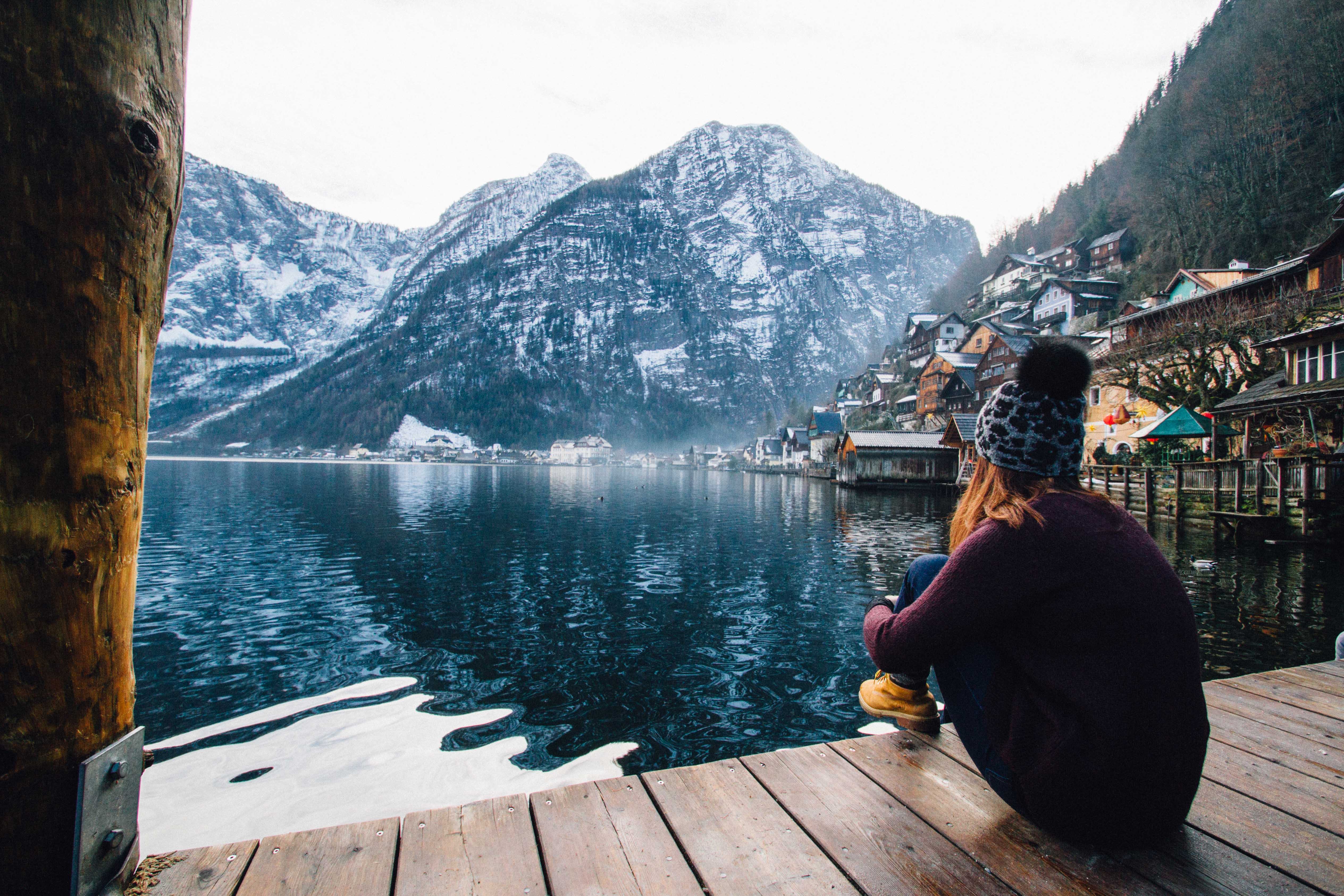Woman in purple sweater sitting on wooden floor with view of lake and mountains photo