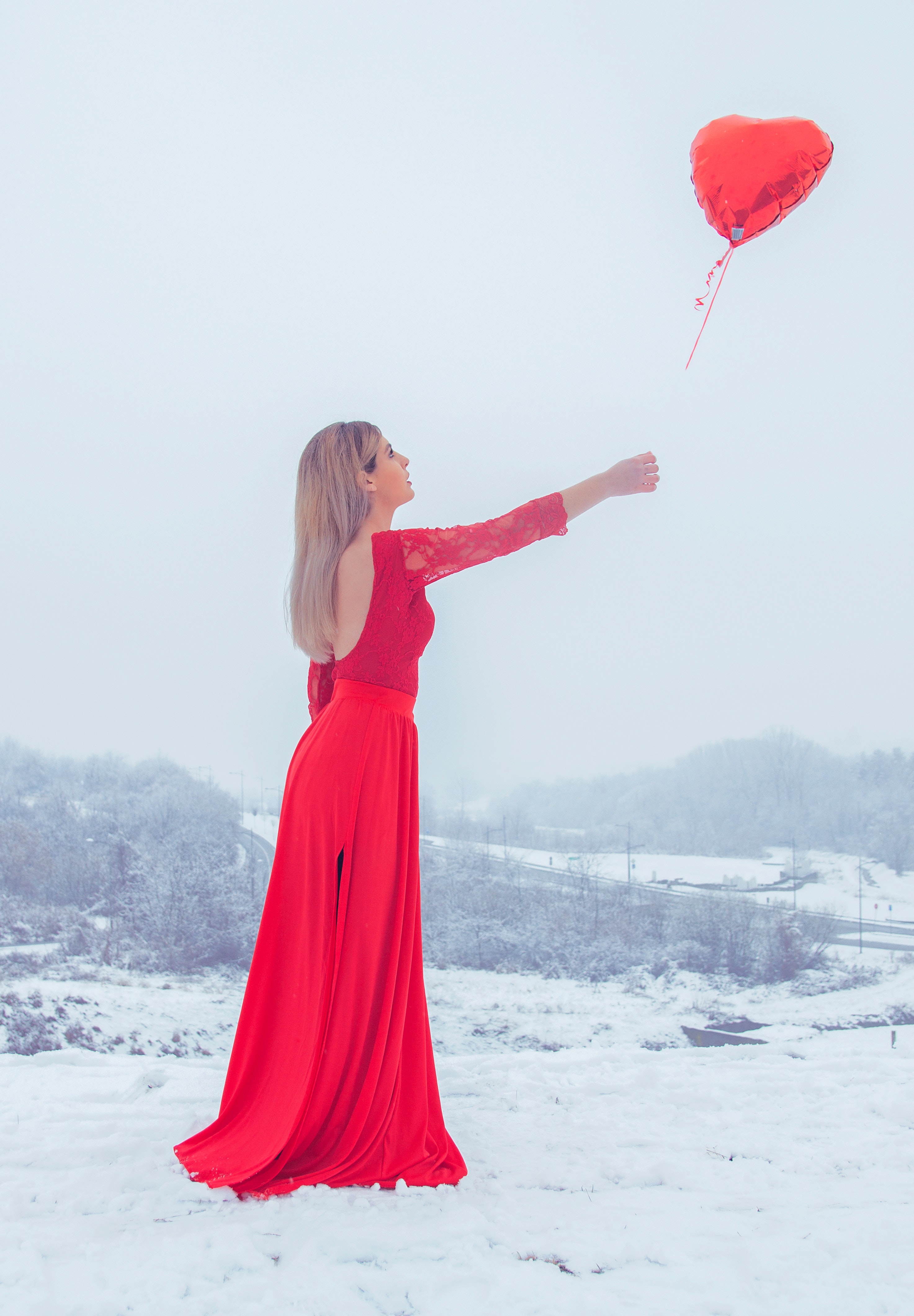 Woman in red floral lace long-sleeved dress standing with red heart balloon photo