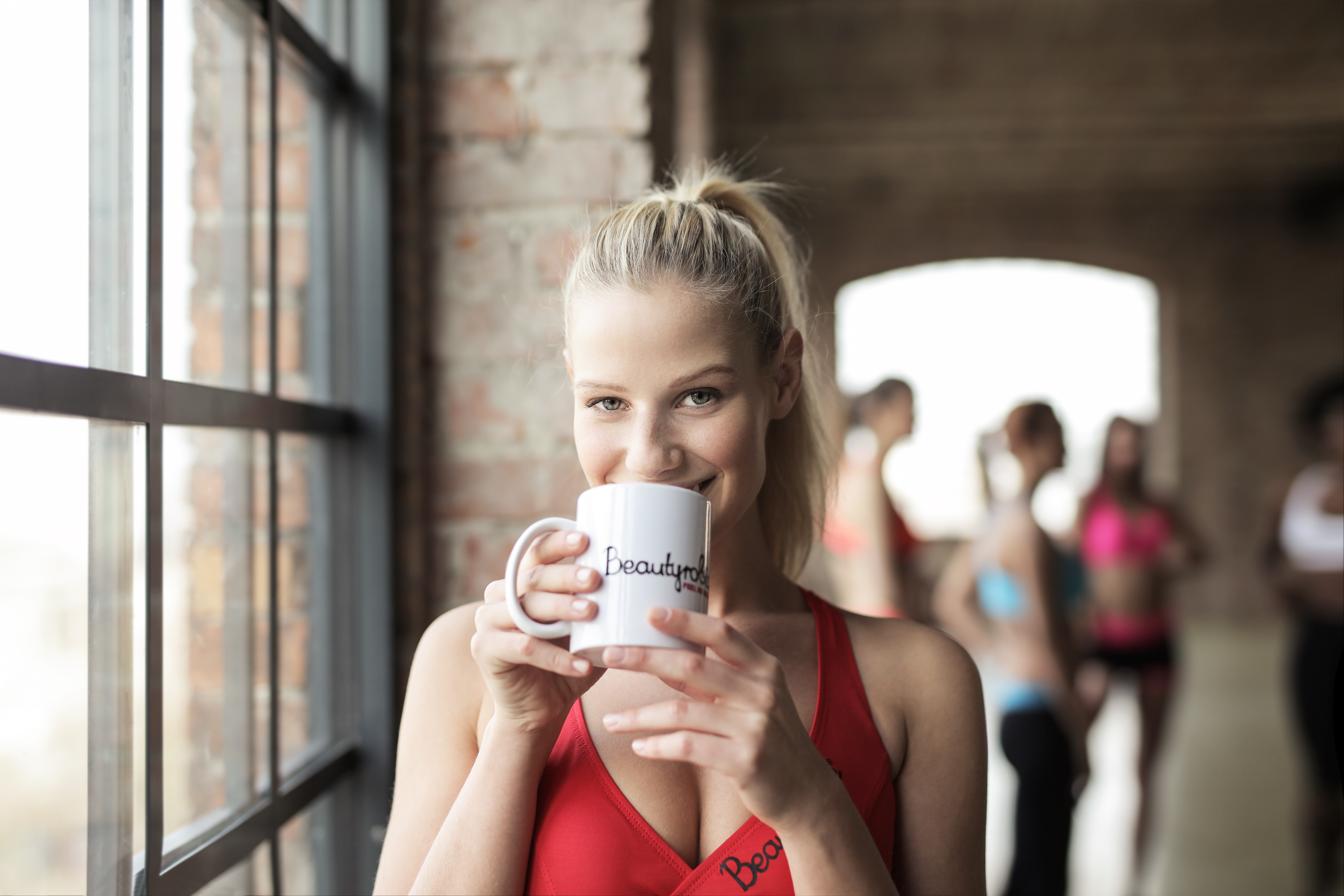 Woman in red scoop-neck tank top holding white mug photo
