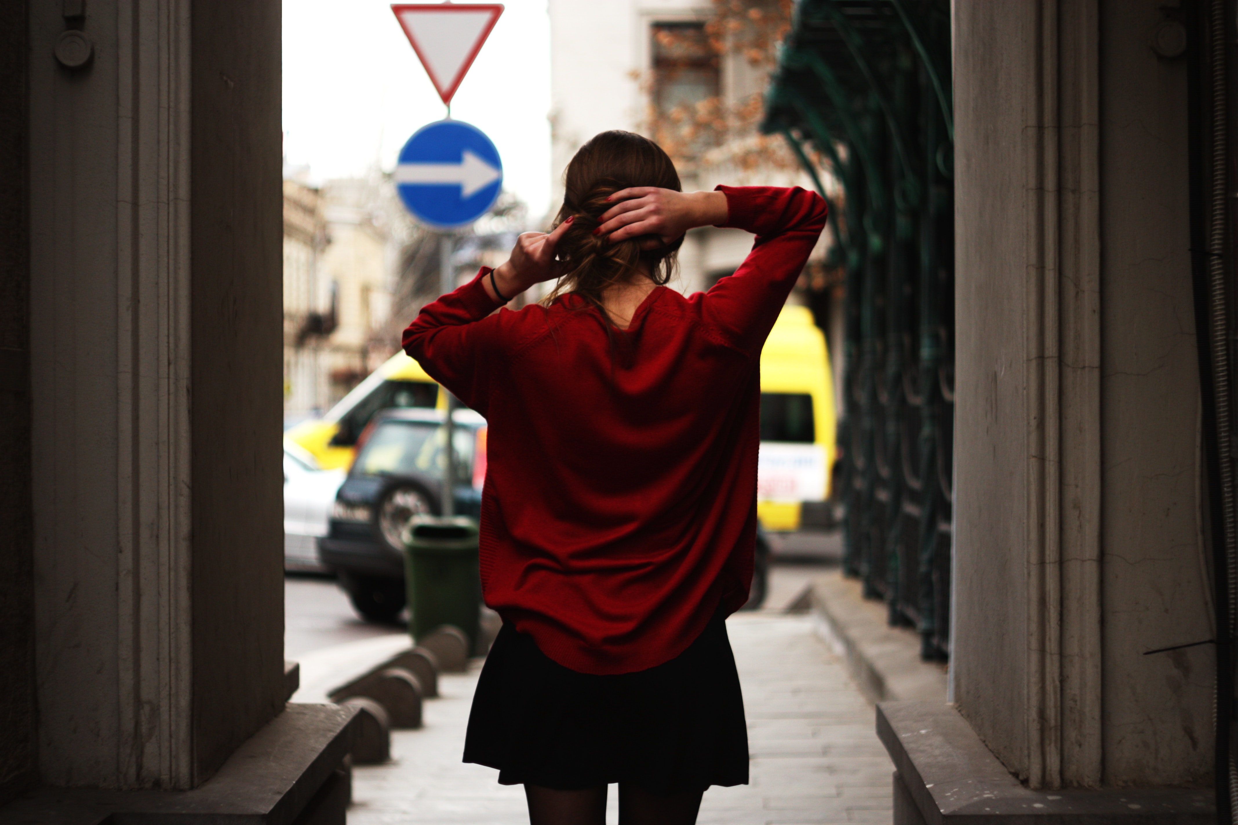 Woman in red sweater and black miniskirt holding hair facing road photo