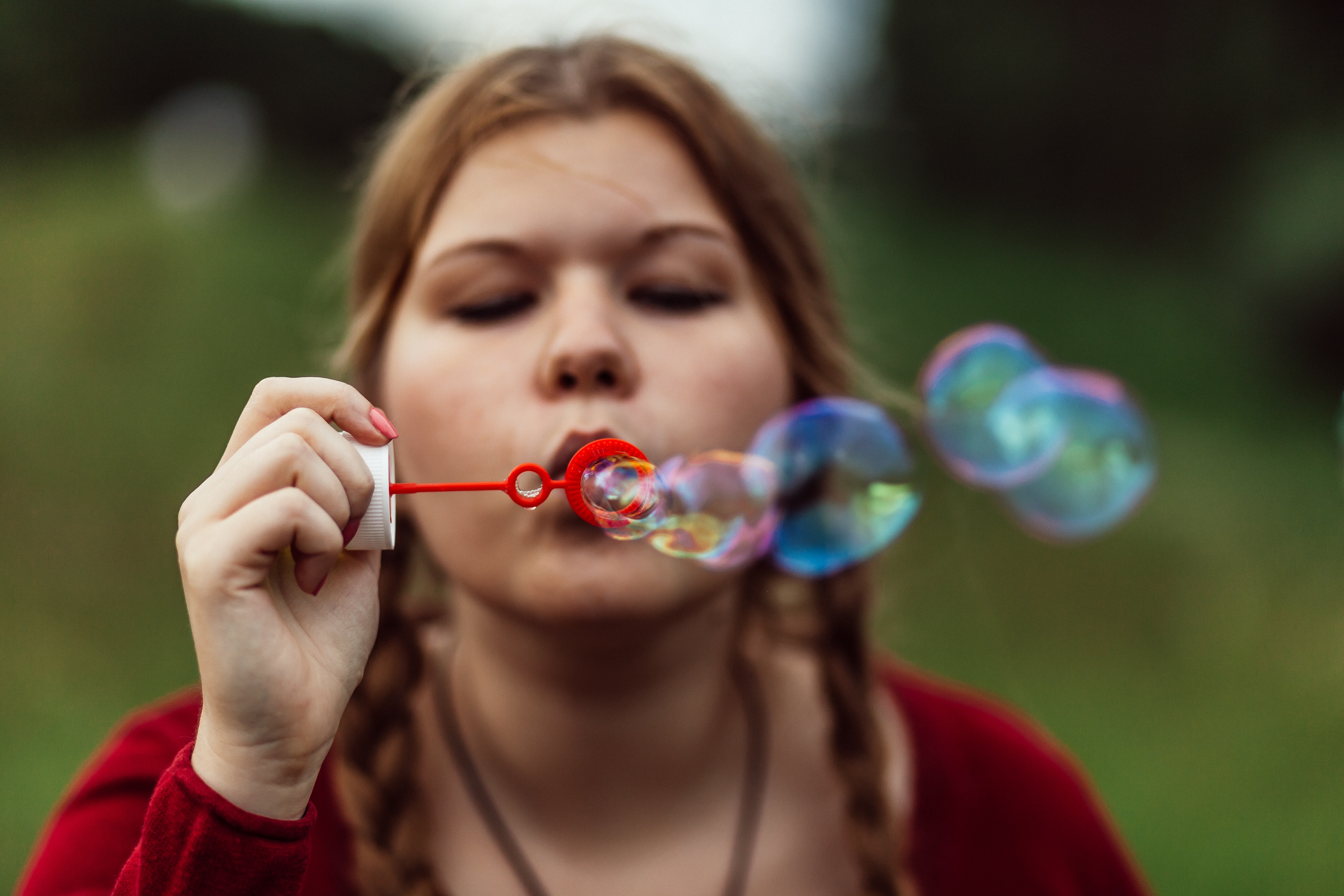 Woman in red top blowing red bubble maker photo
