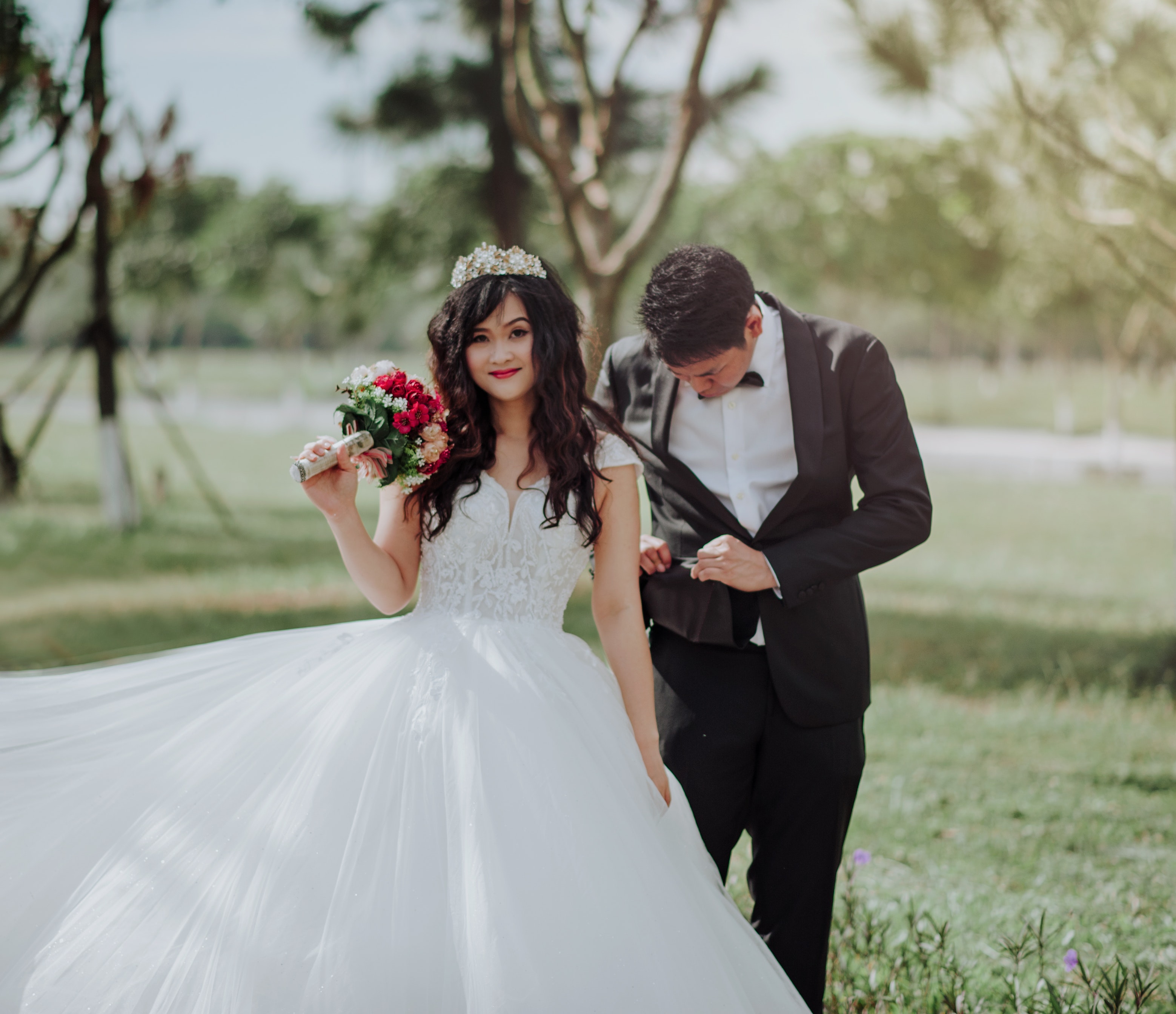 Woman in wedding dress holding flower with man in black blazer photo