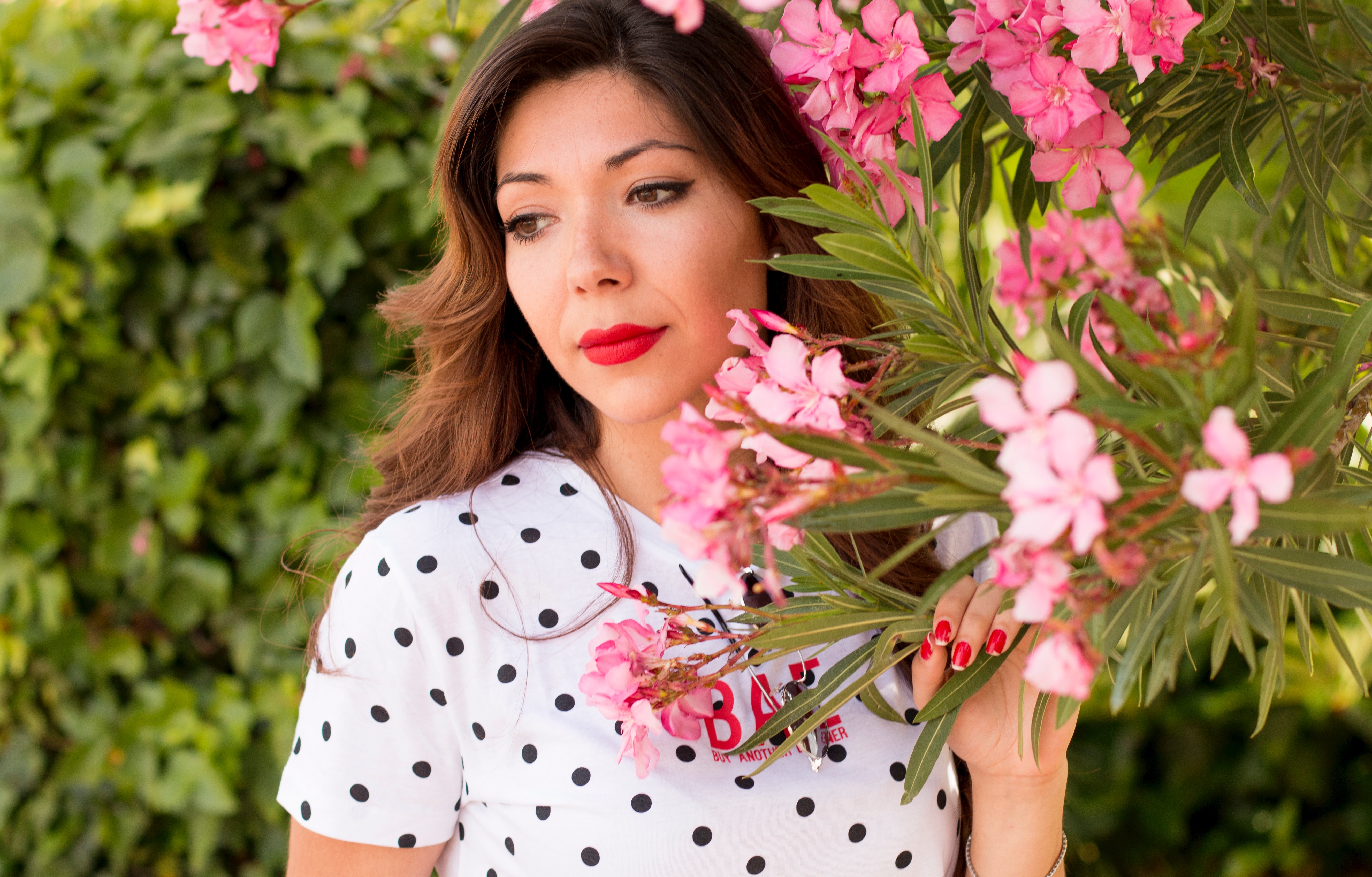 Woman in white and black polka dots dress near pink flowers during daylight photo