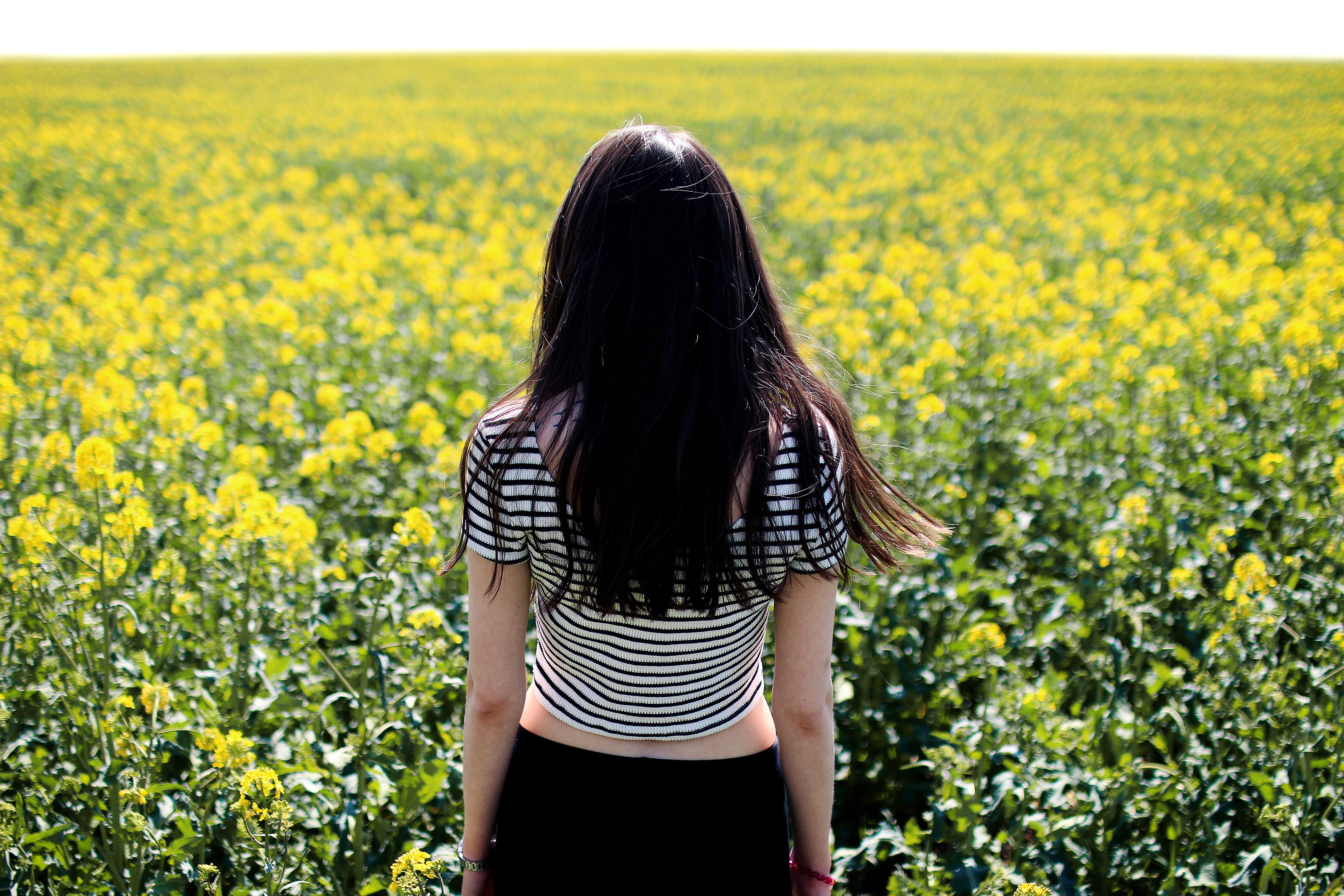 Woman in white and black striped crop top facing field photo