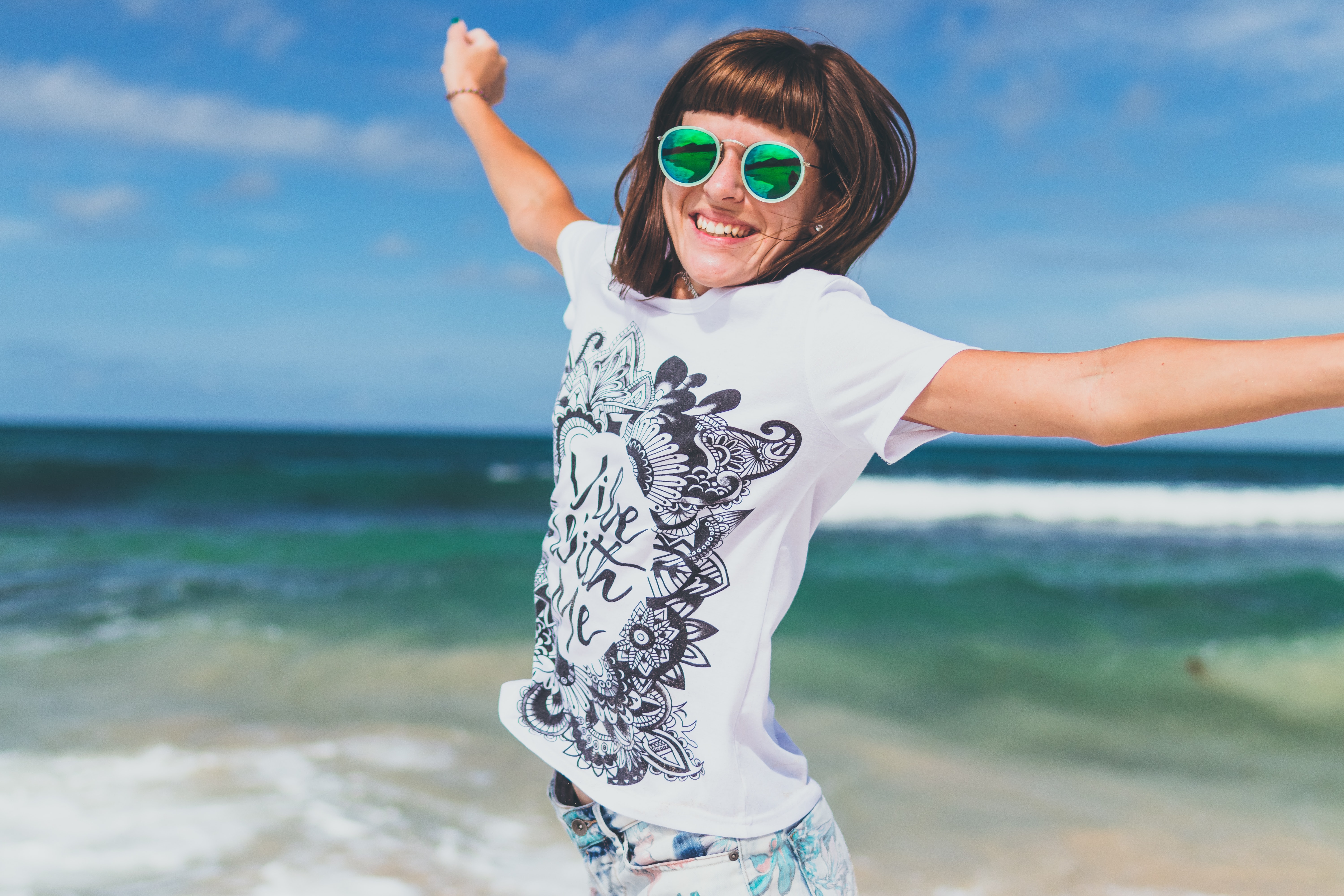 Woman in white and black t-shirt lifting hands smiling on seashore photo