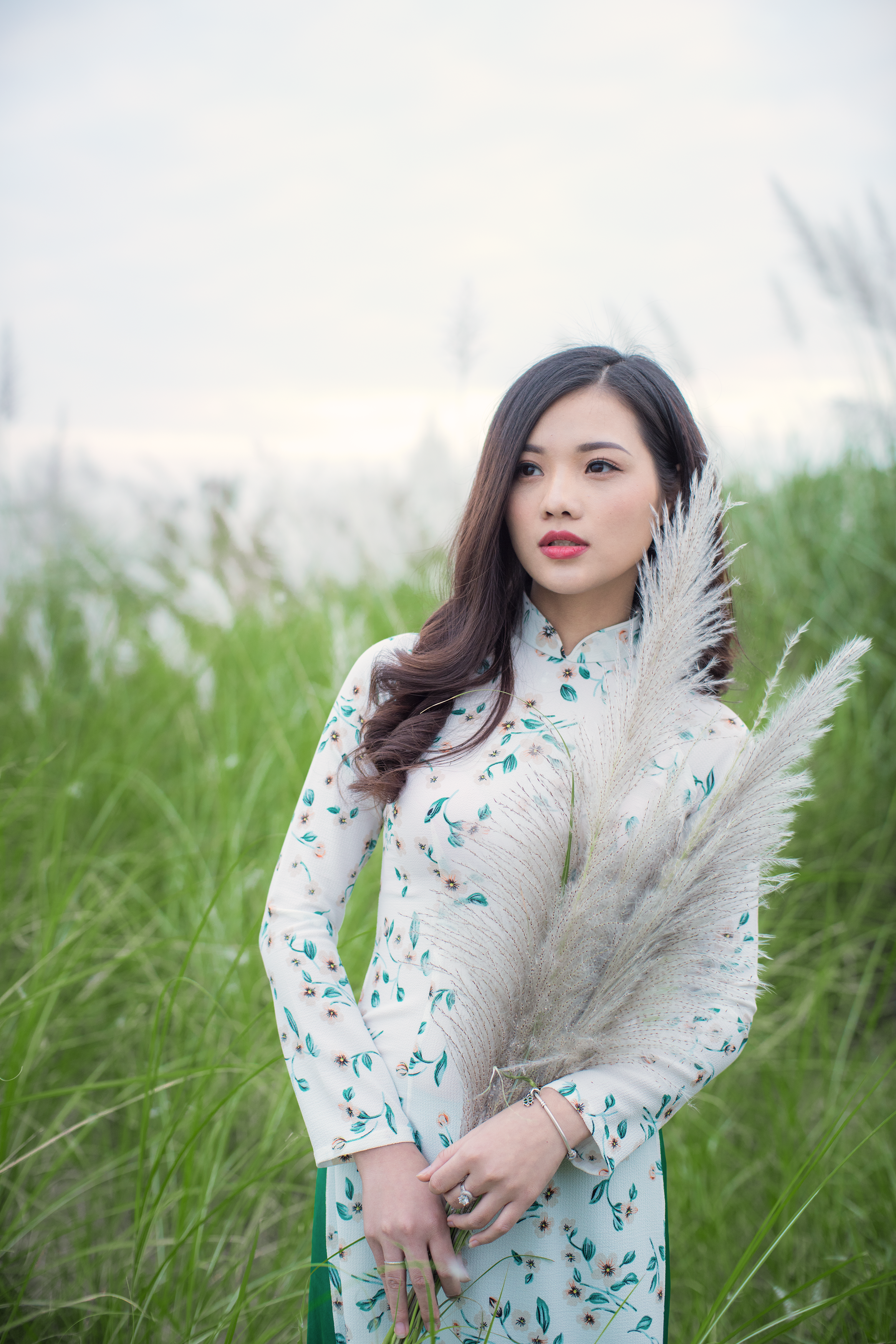 Woman in white and green long-sleeved traditional dress standing next-to green grasses photo