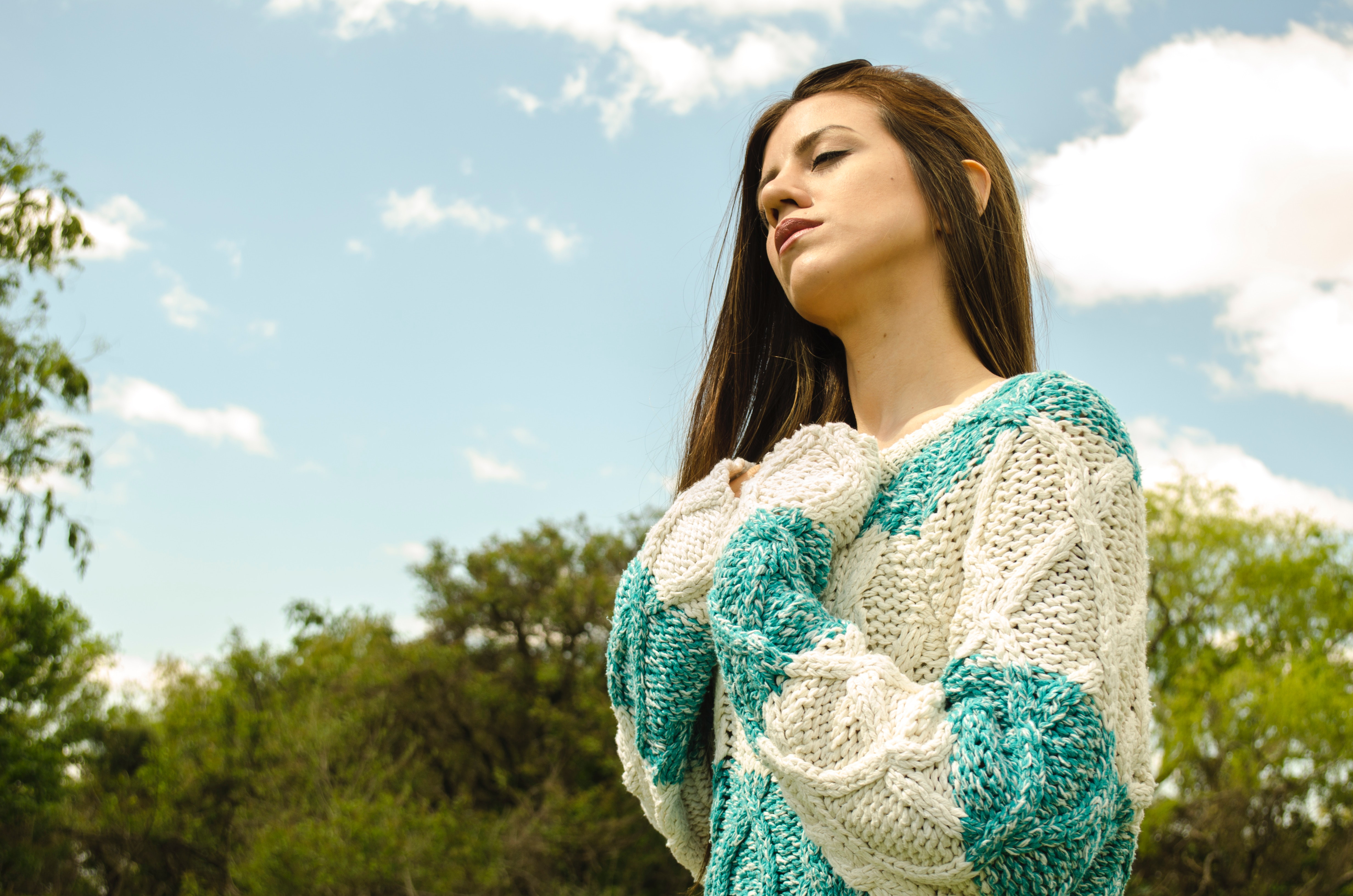 Woman in white and teal crochet dress under cloudy sky photo