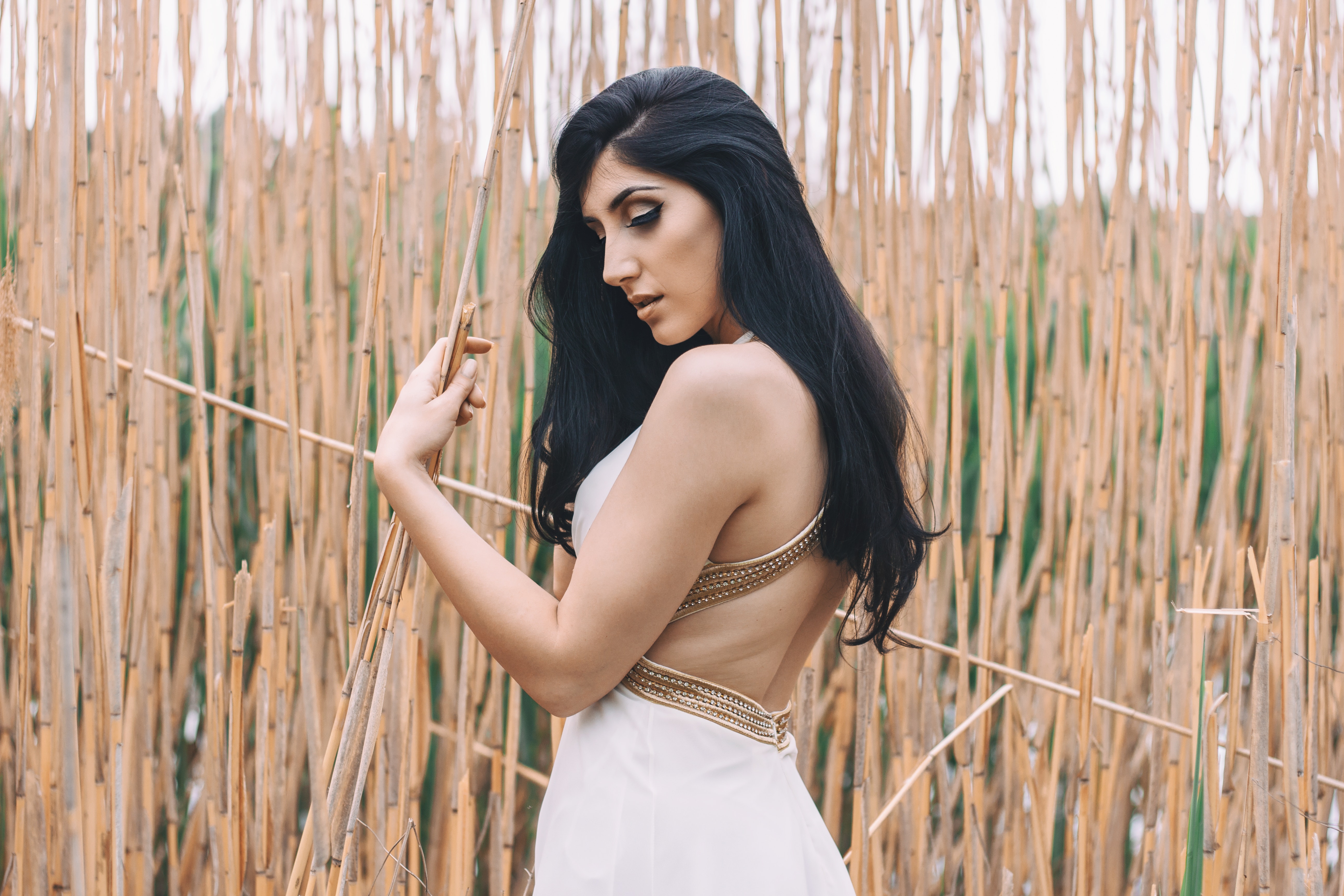 Woman in white backless dress in front of bamboo sticks photo