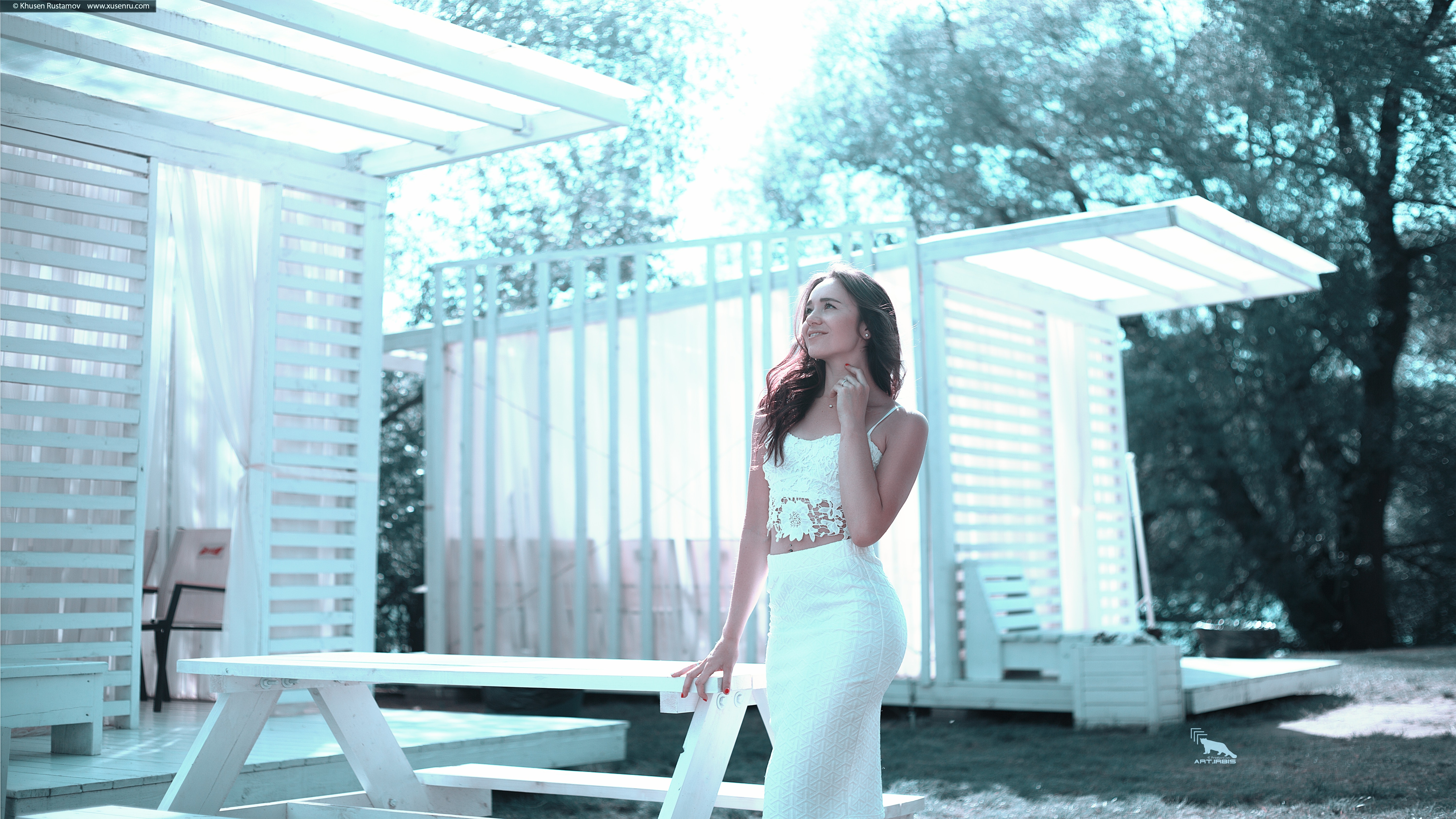 Woman in white dress standing beside white wooden picnic table photo