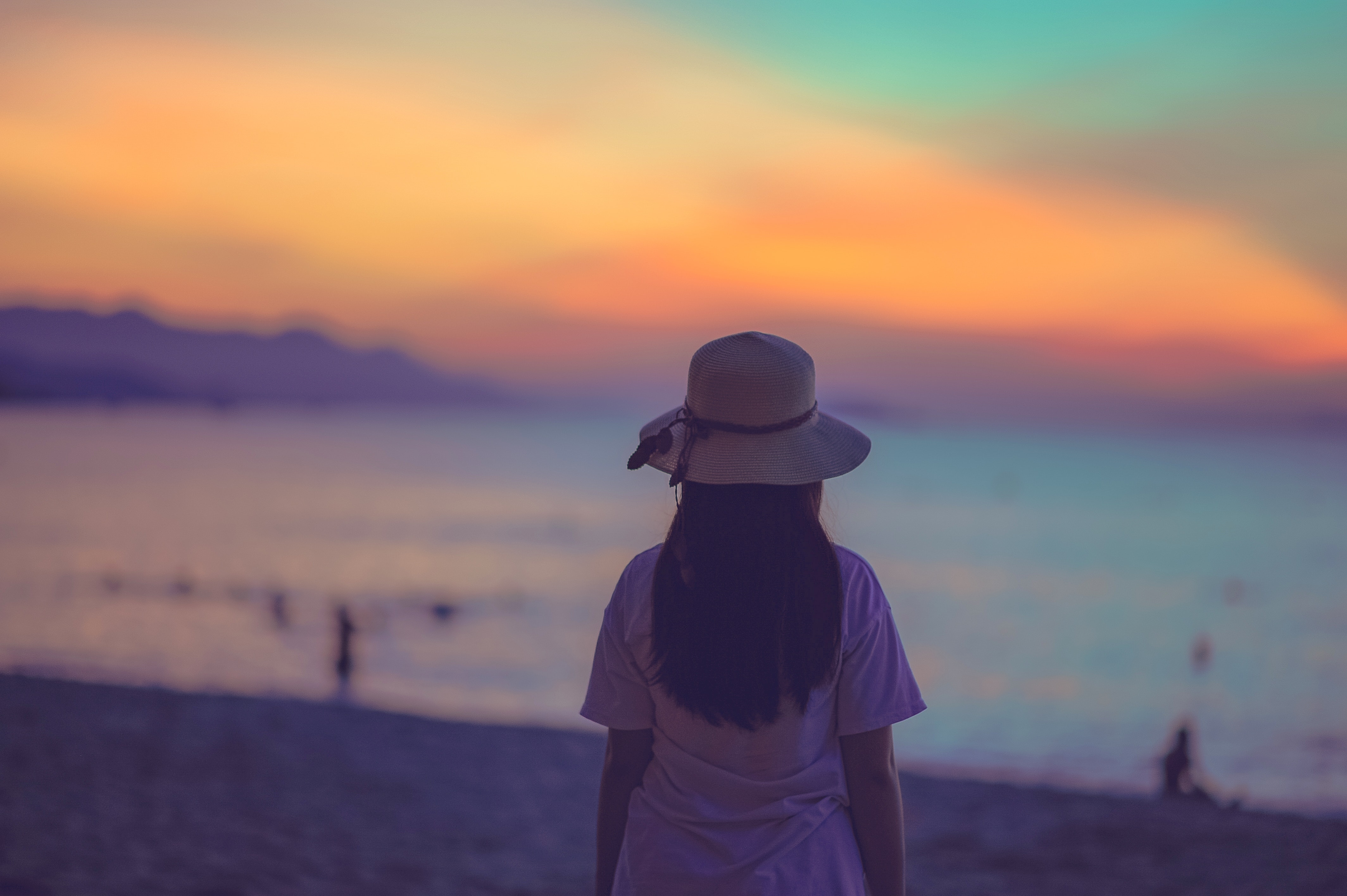 Woman in white dress standing near beach during sunset photo