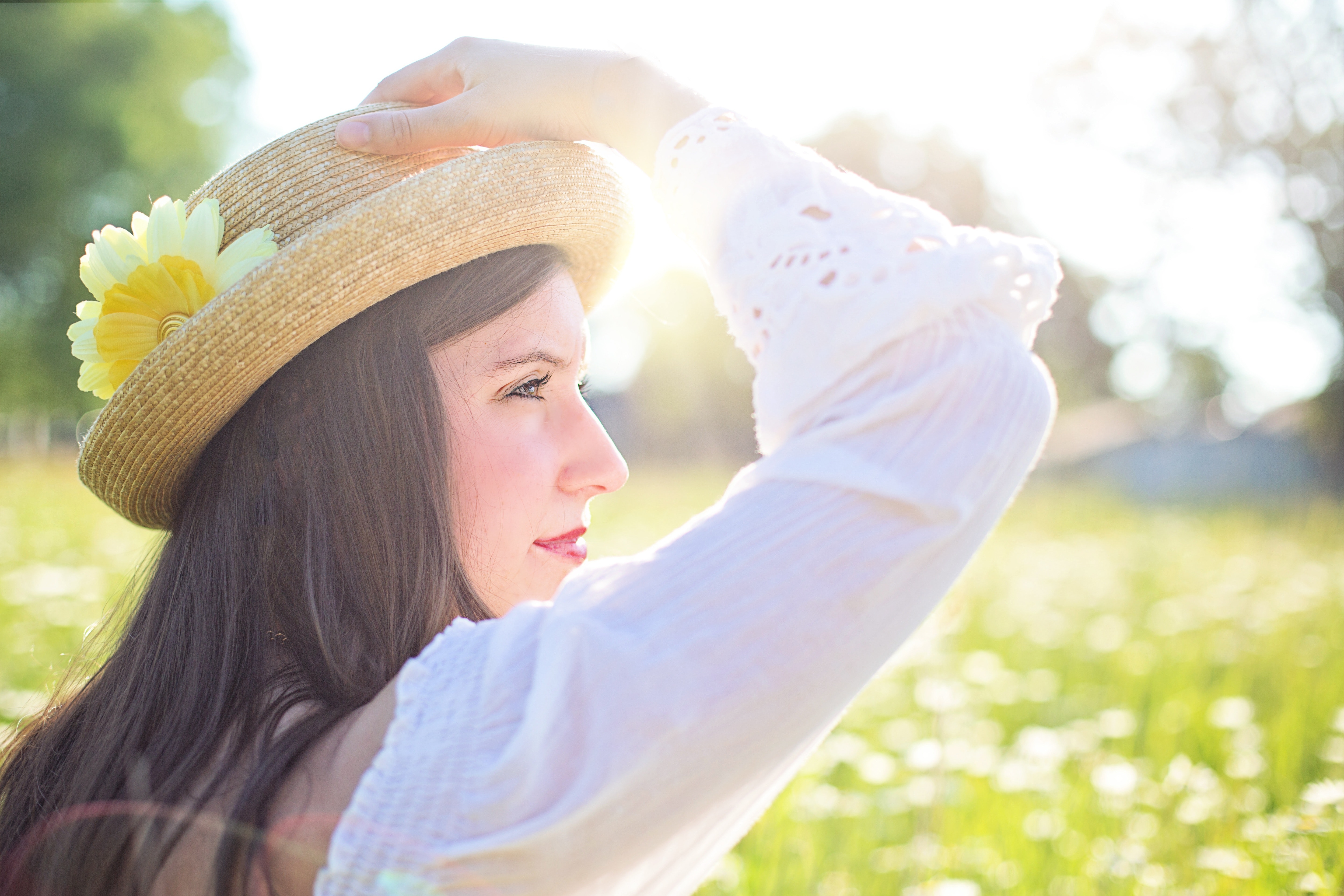Woman in white long sleeve shirt wearing a straw hat during daytime at flower field photo