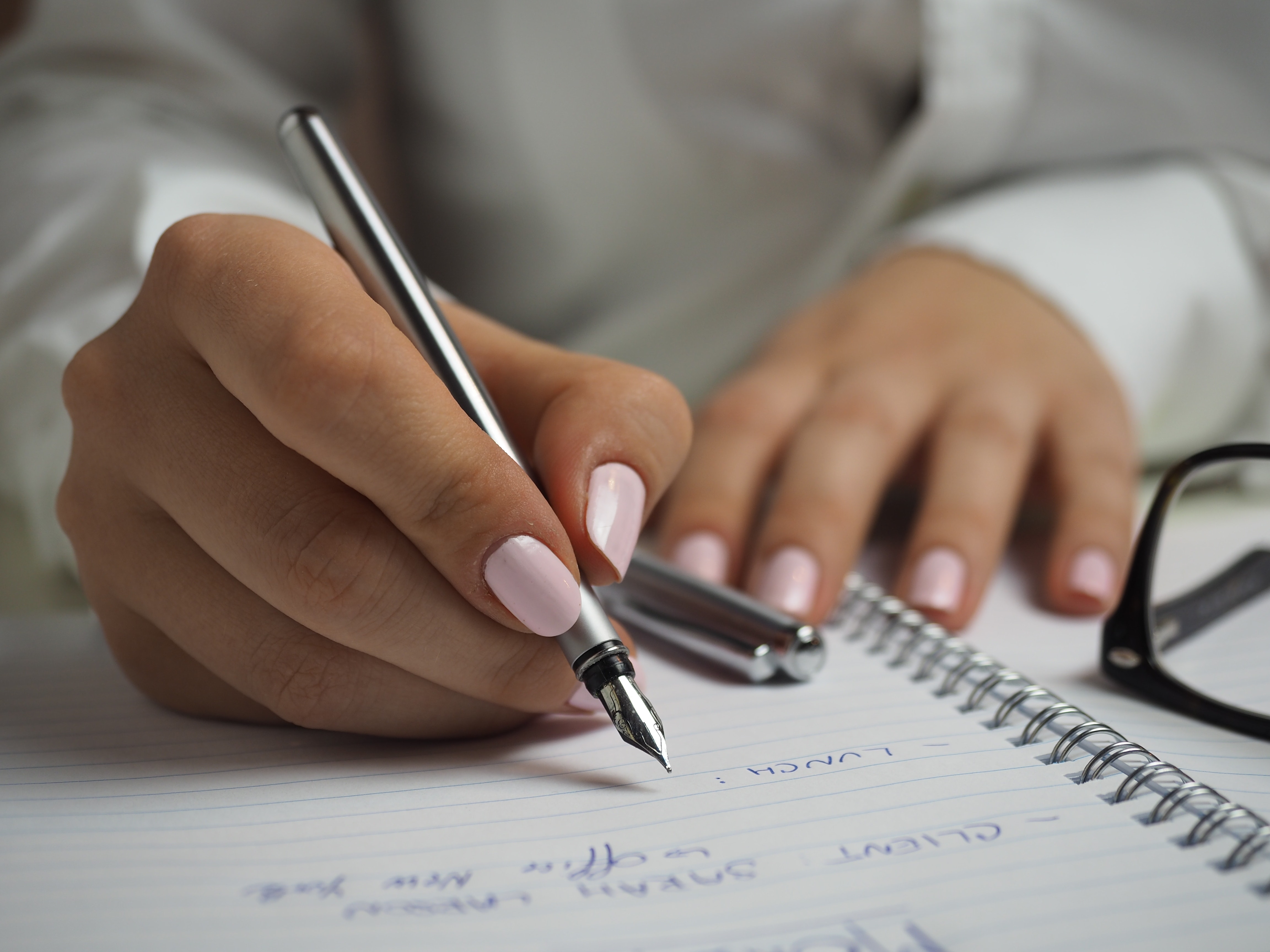 Woman in white long sleeved shirt holding a pen writing on a paper photo