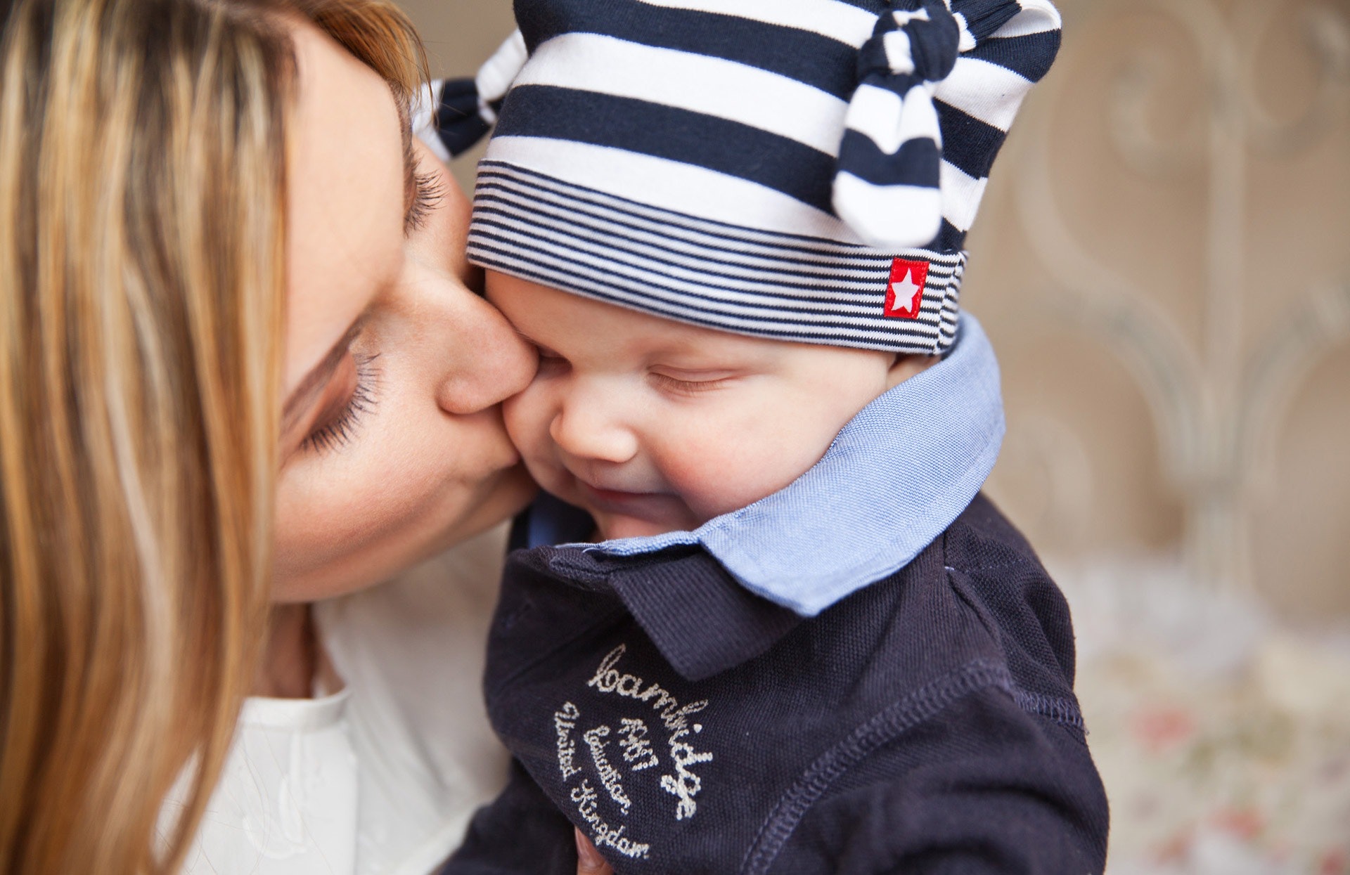Woman in white shirt kissing baby with black and white stripe knit cap photo