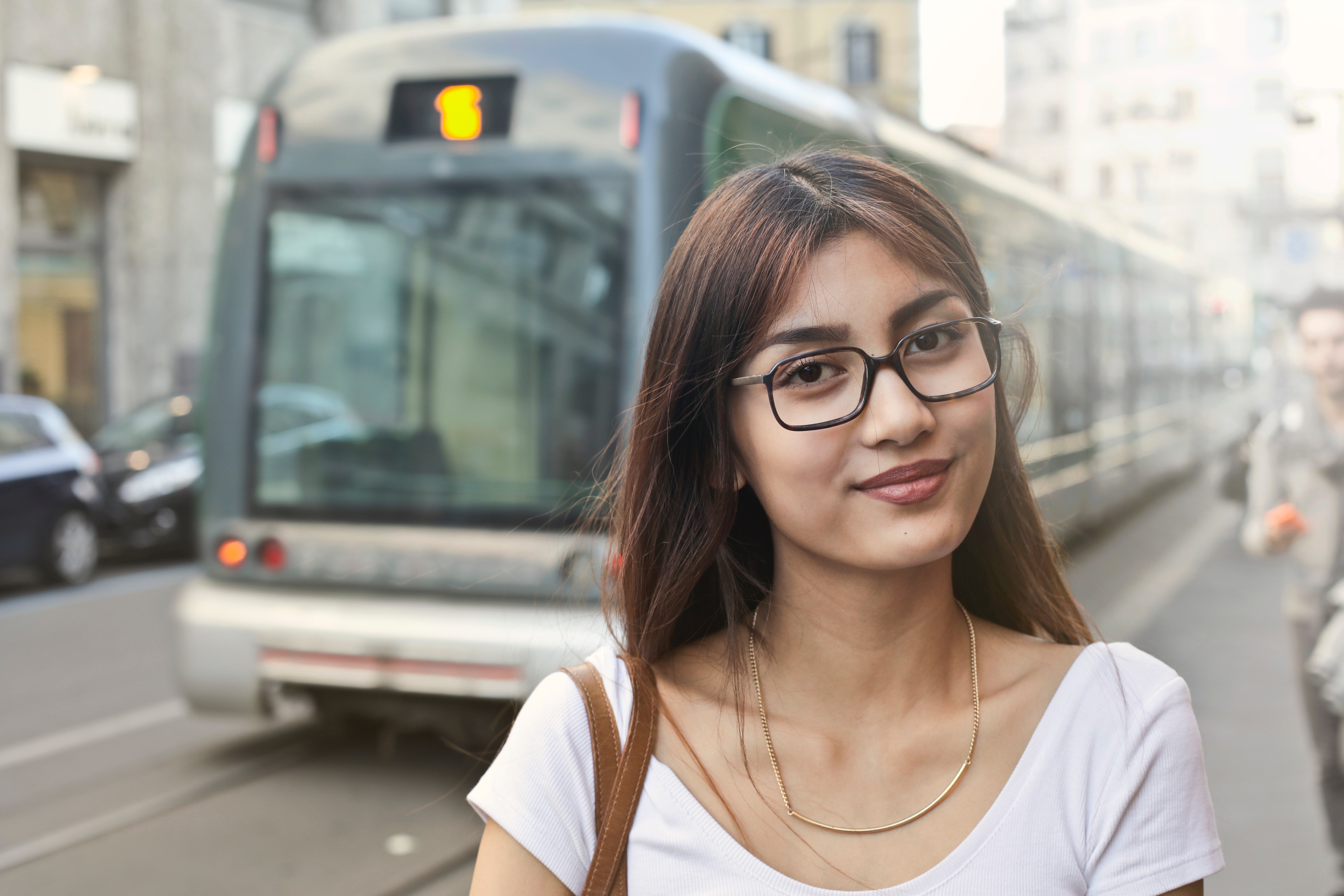 Woman in white shirt with eyeglasses standing near train photo