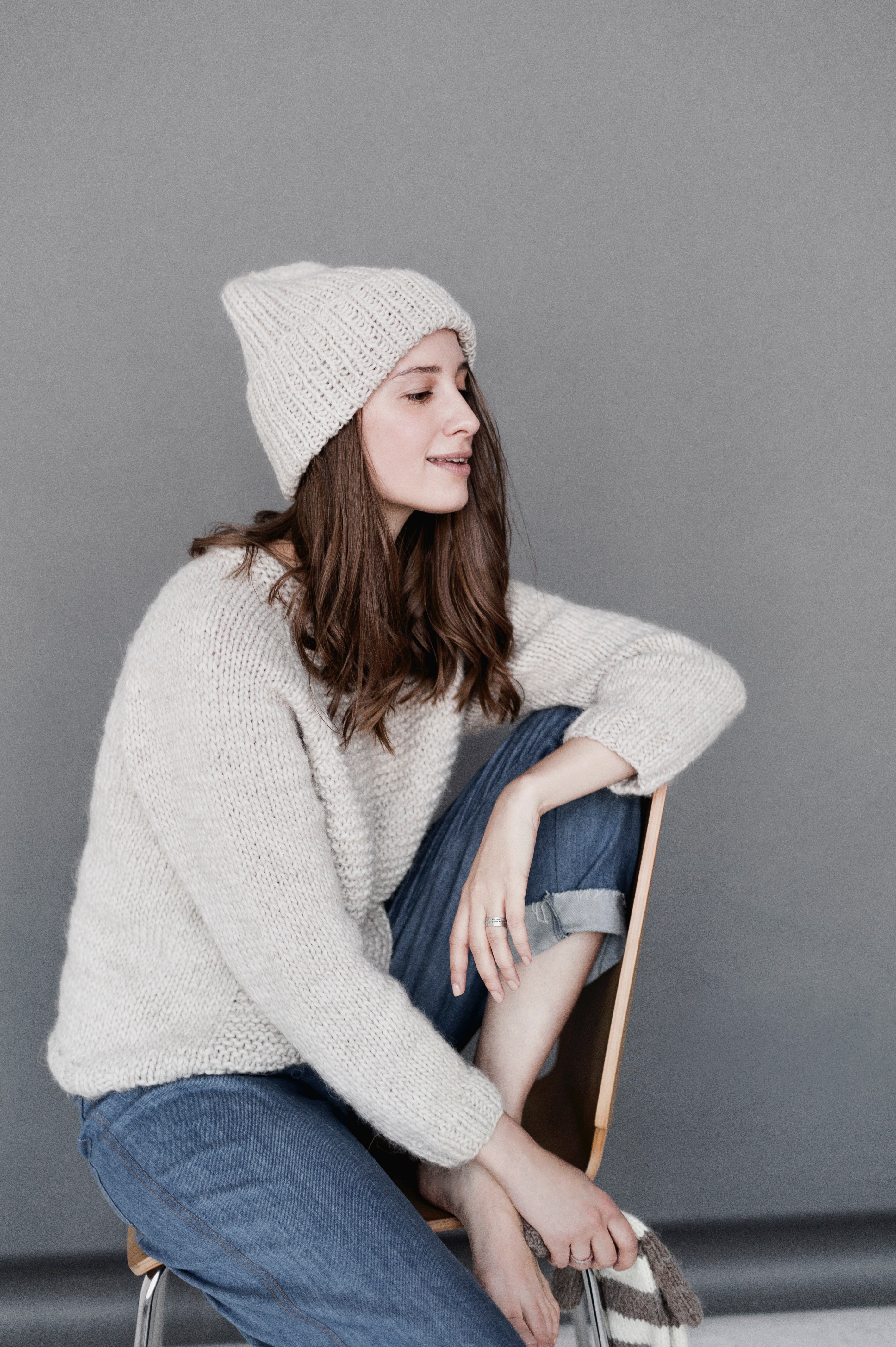 Woman in white sweater and beanie with blue denim pants photo